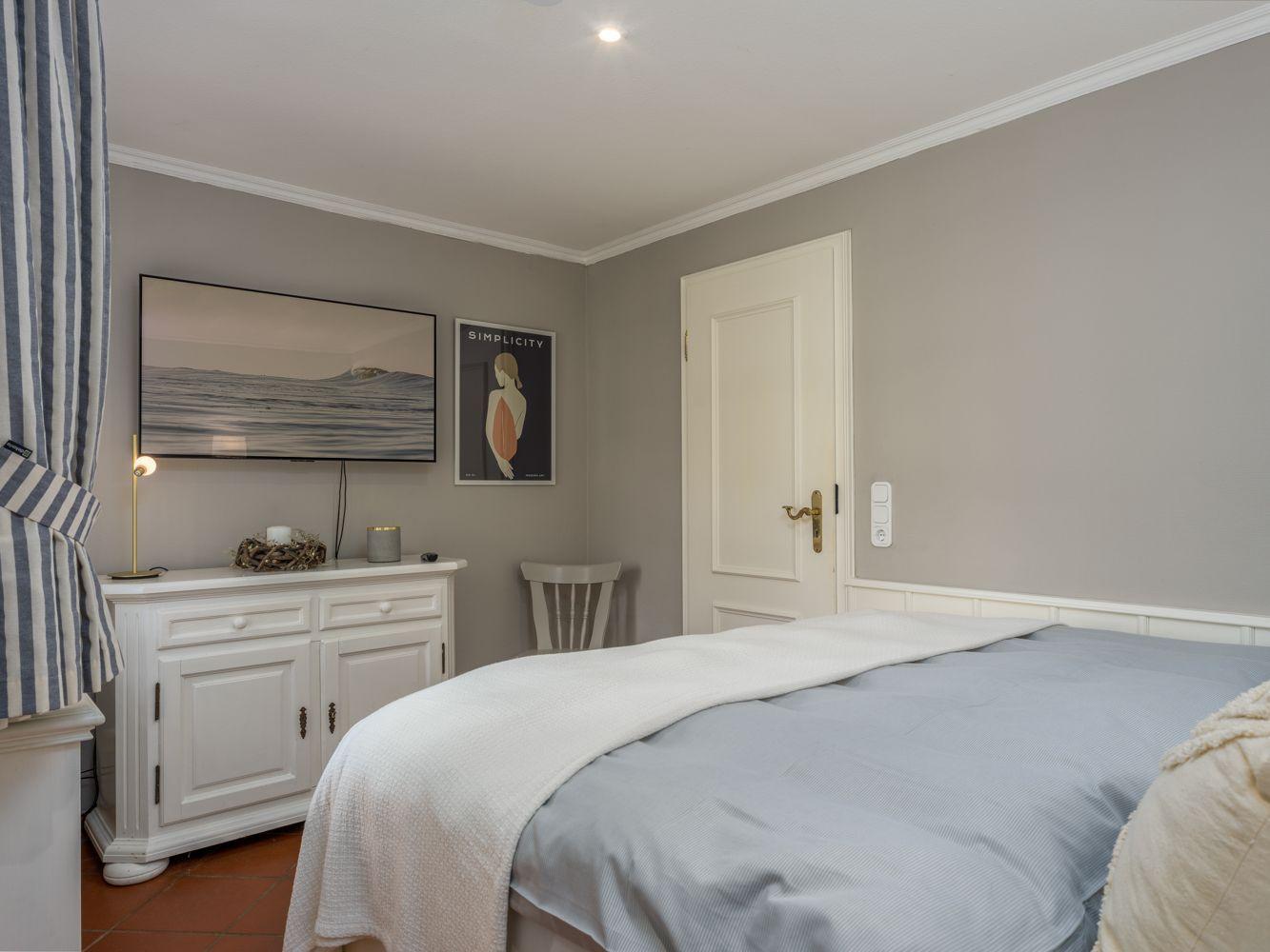Schlafzimmer mit Bett, Schrank und Wandbildern