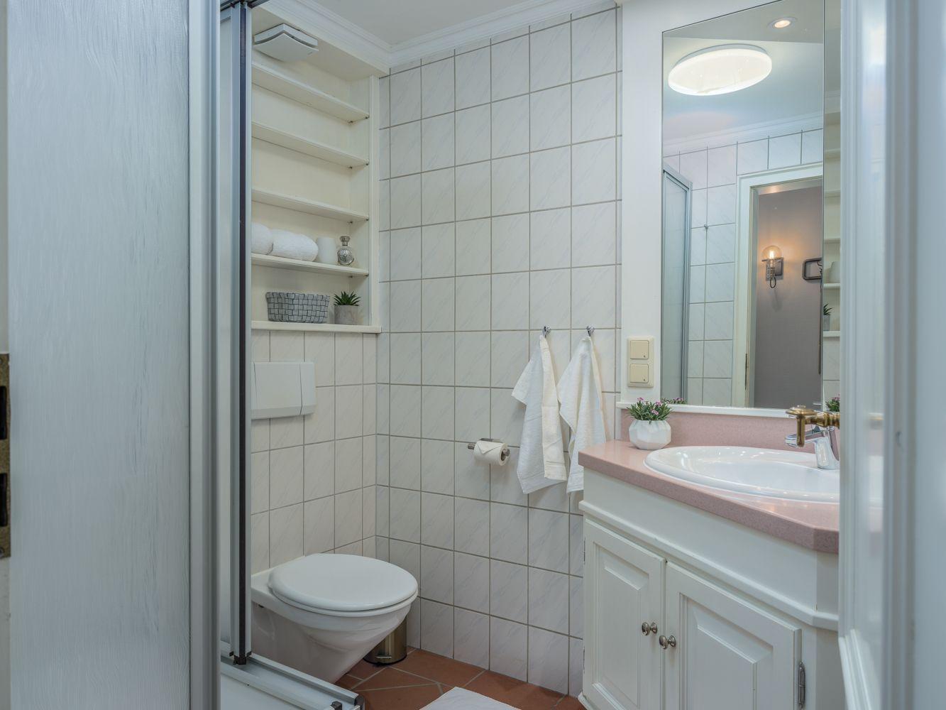 Badezimmer mit Waschbecken, Spiegel, Toilette und Dusche