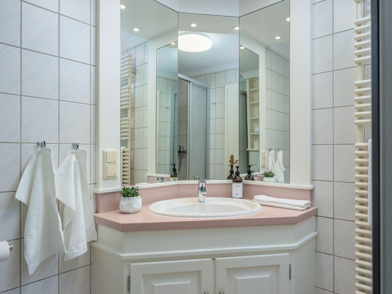 Badezimmer mit Waschtisch, Spiegel und Dusche