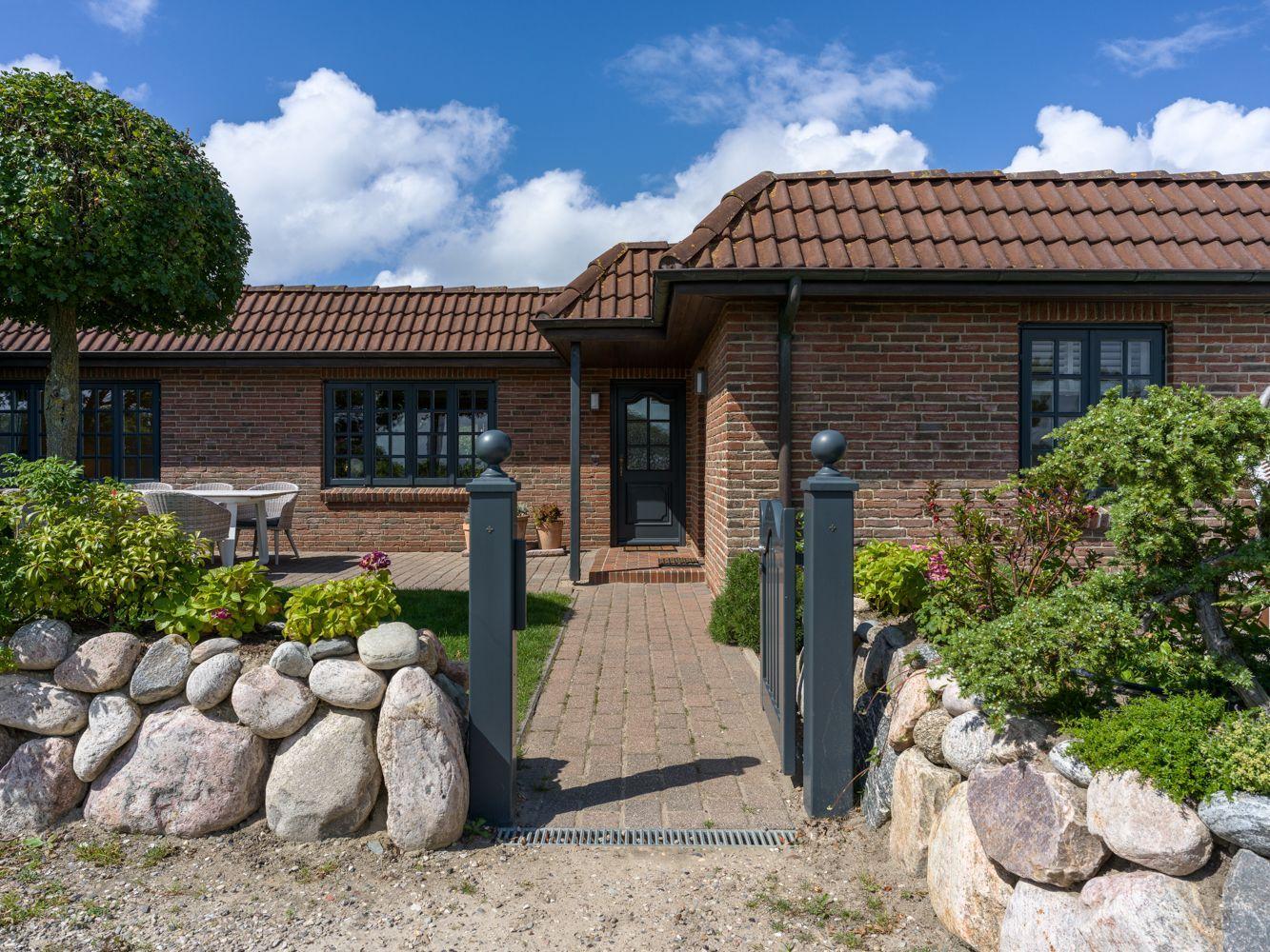 Ein Haus mit Backsteinfassade, rotem Dach und gepflastertem Weg zur Eingangstür.