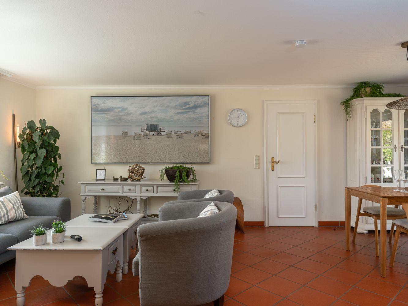 Wohn- und Essbereich mit Sofa, Stühlen, Tisch und Wandbild.