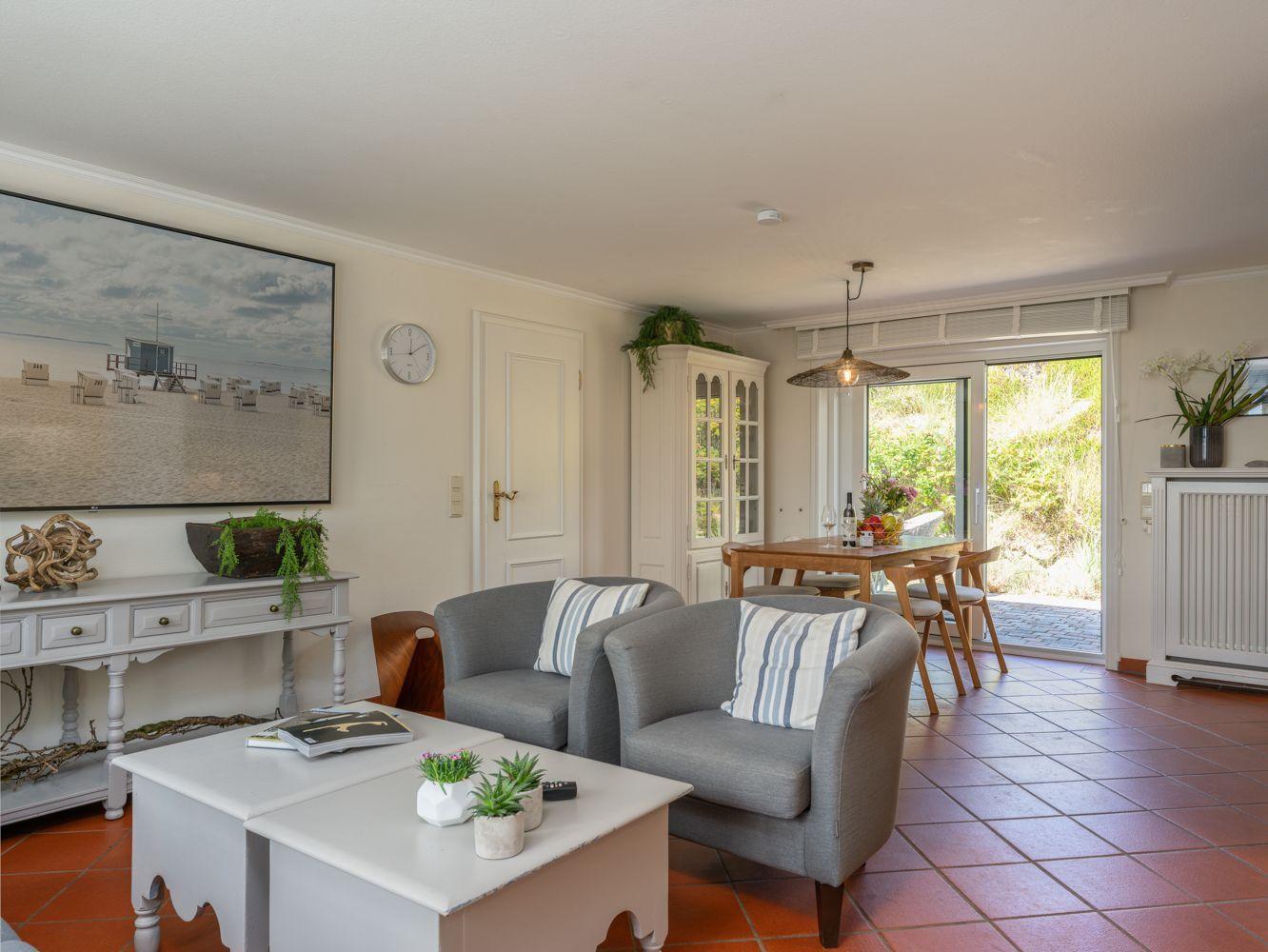 Wohn- und Essbereich mit Sitzgelegenheiten, Tisch, Stühlen und Blick auf Garten.