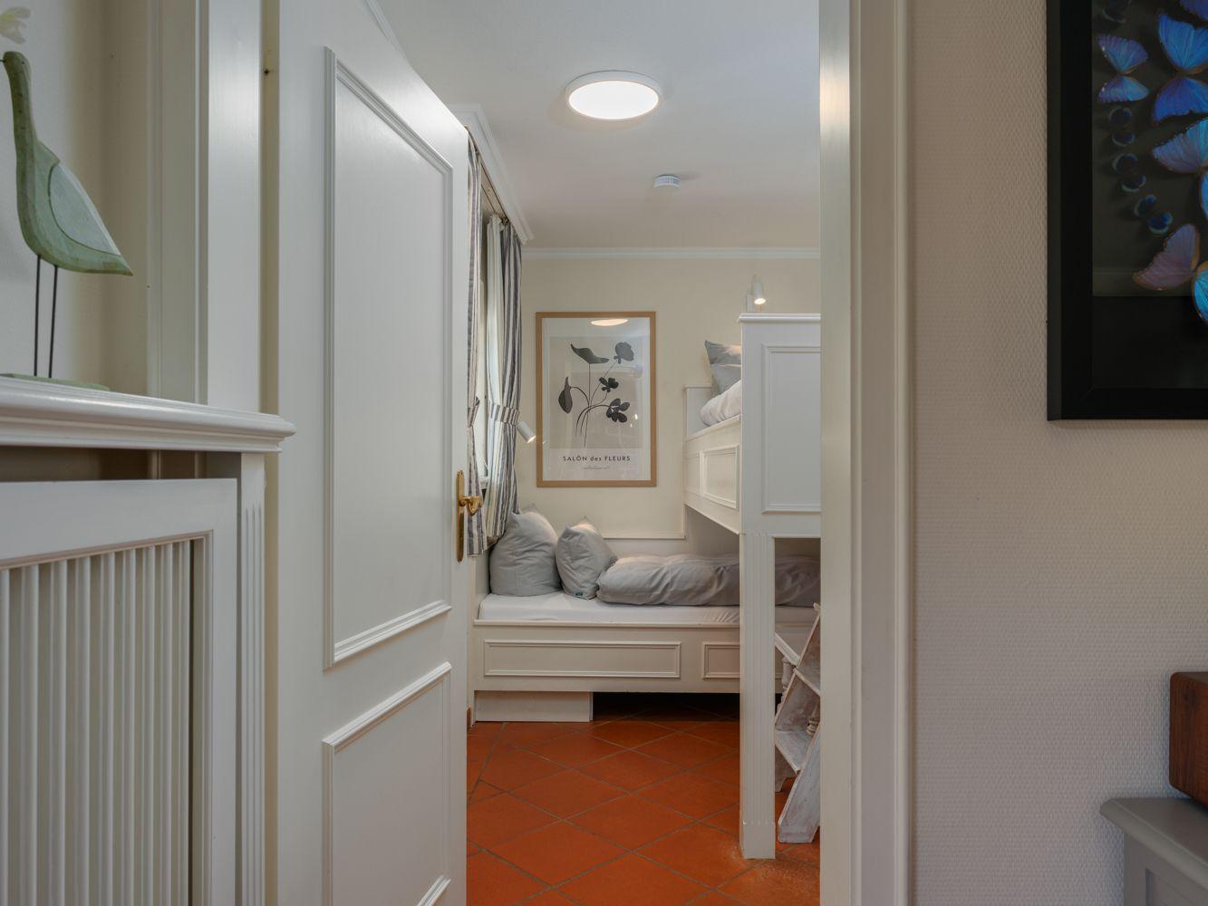 Schlafzimmer mit Doppelbett und Wandbild. Terrakottafußboden und weiße Möbel.