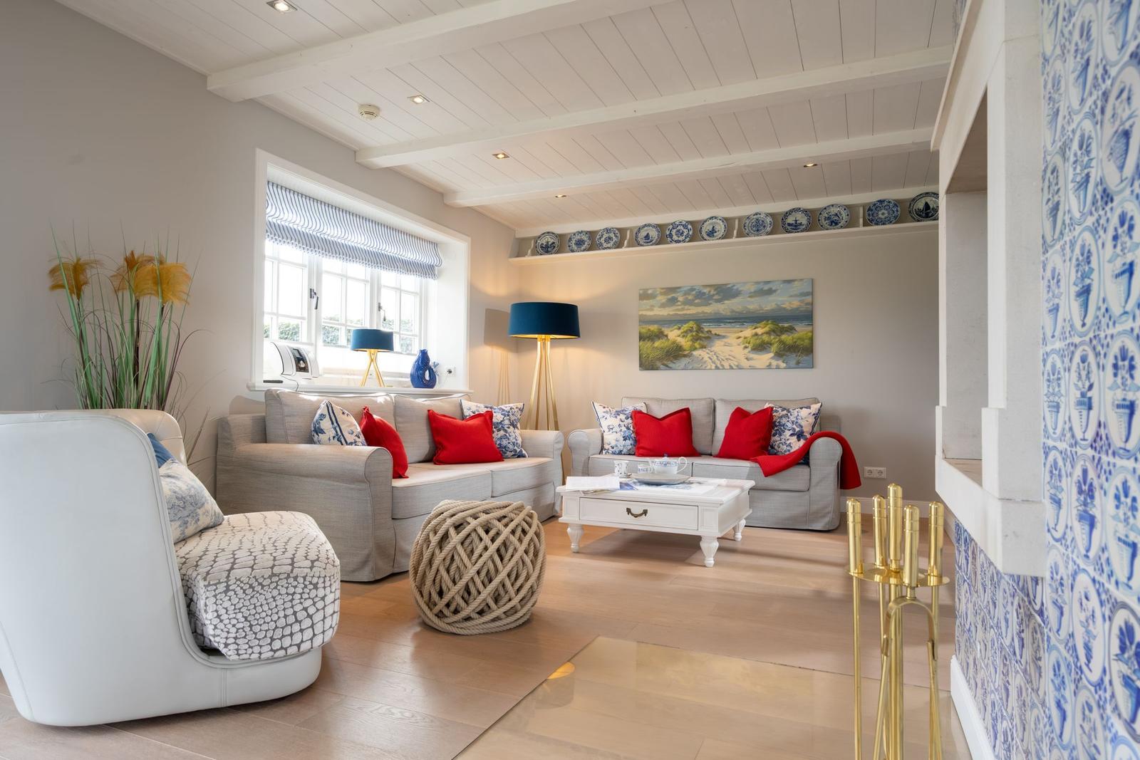 Wohnzimmer mit Sofa, Sessel, Couchtisch und Wandfliesen. Fenster mit Rollladen und Wanddekoration.