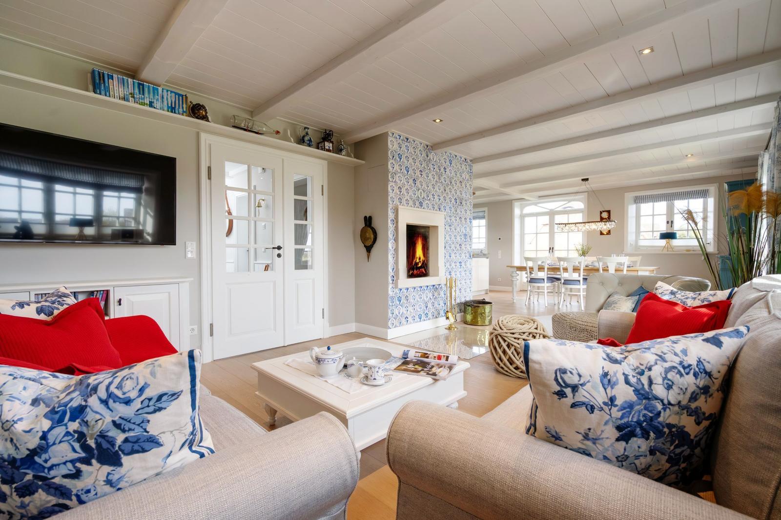 Wohnzimmer mit Kamin, Sofa, Couchtisch und Fernseher. Blick in Esszimmer.