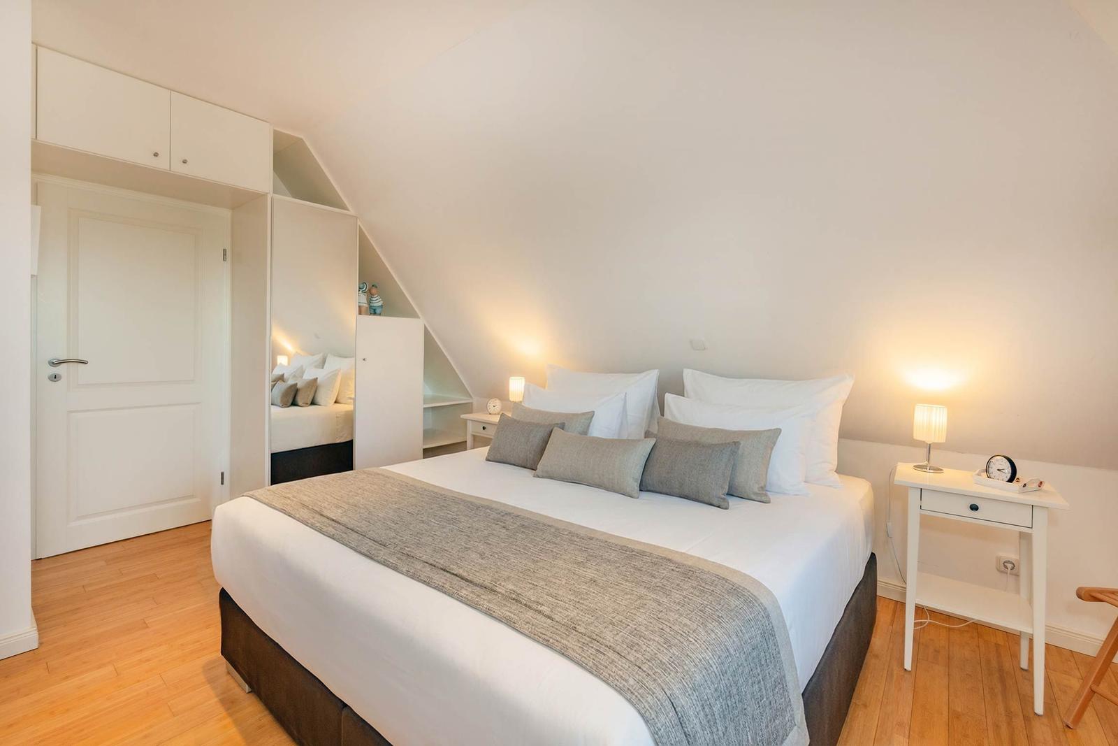 Schlafzimmer mit Dachschrägen, Bett, Nachttisch und Kleiderschrank.