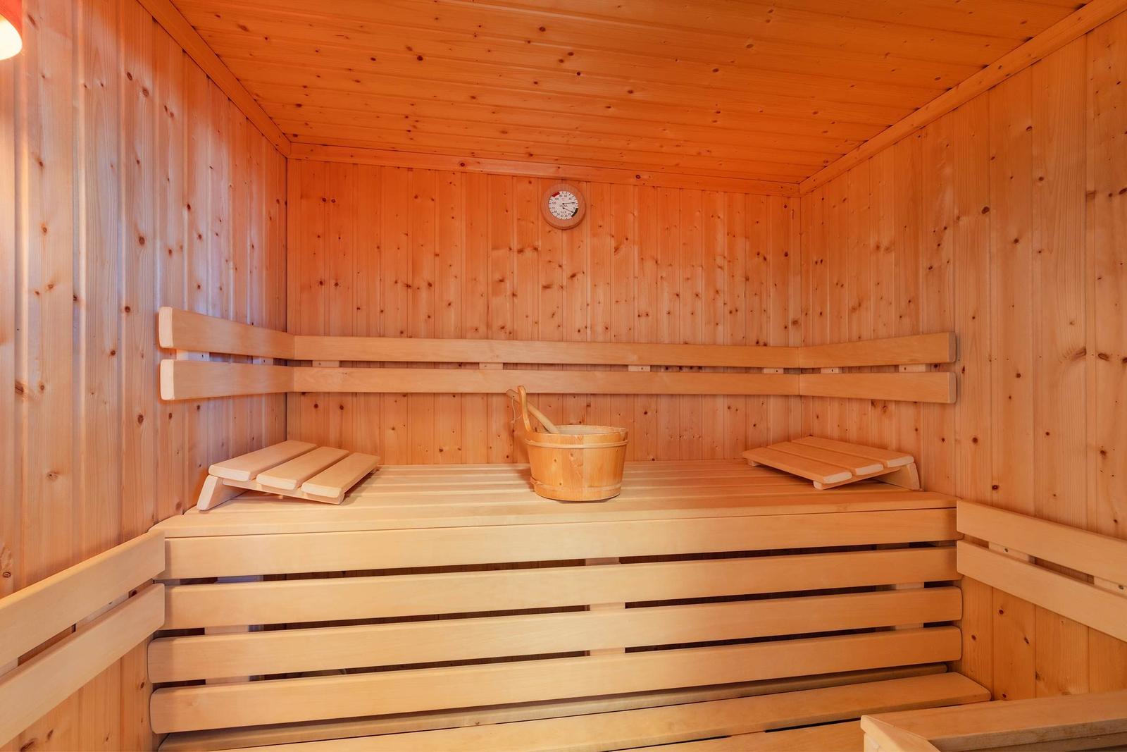 Sauna mit Holzbank, Eiche und Thermometer an der Wand.