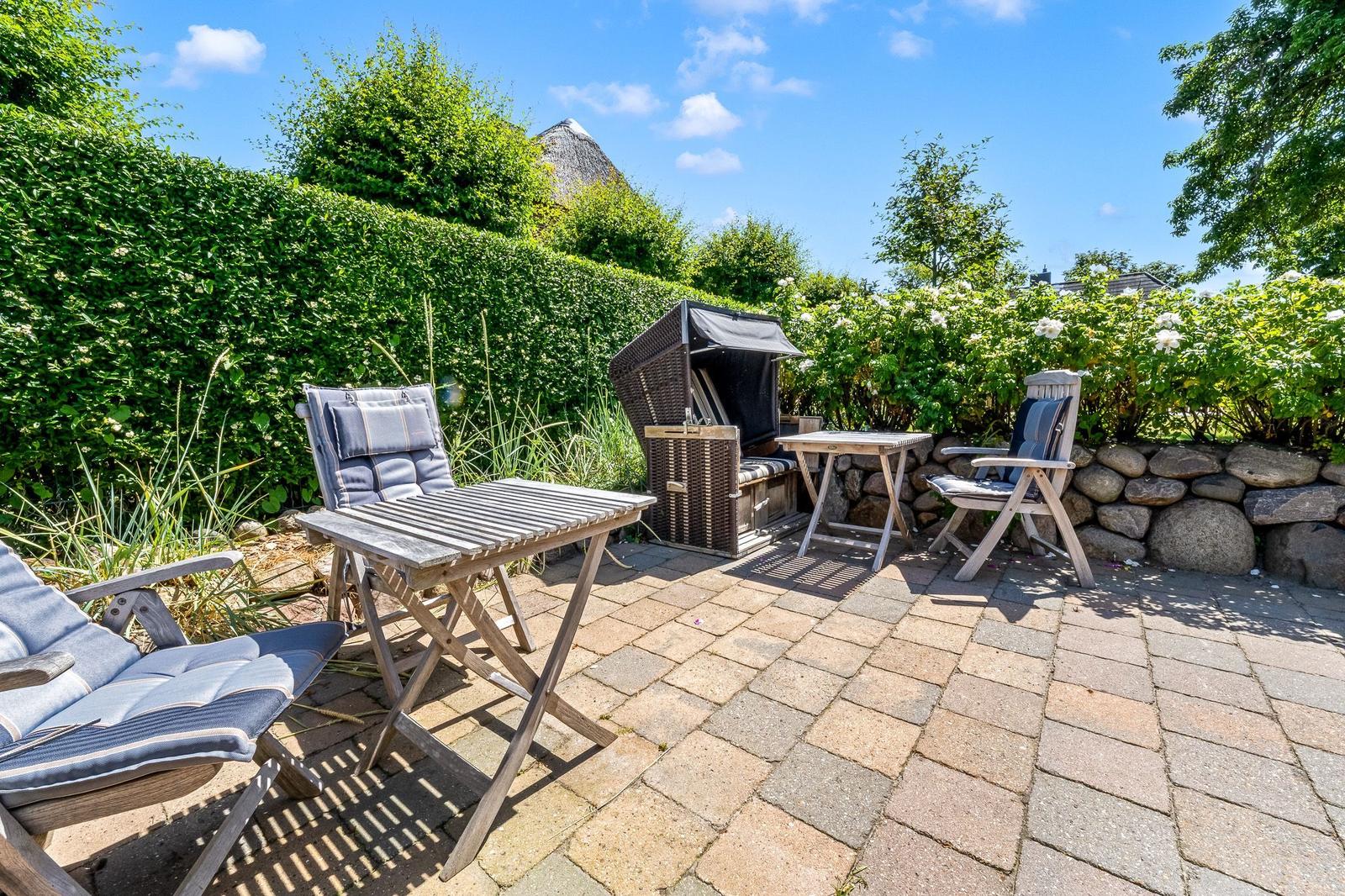Terrace with garden furniture, grill, and plants in the background.