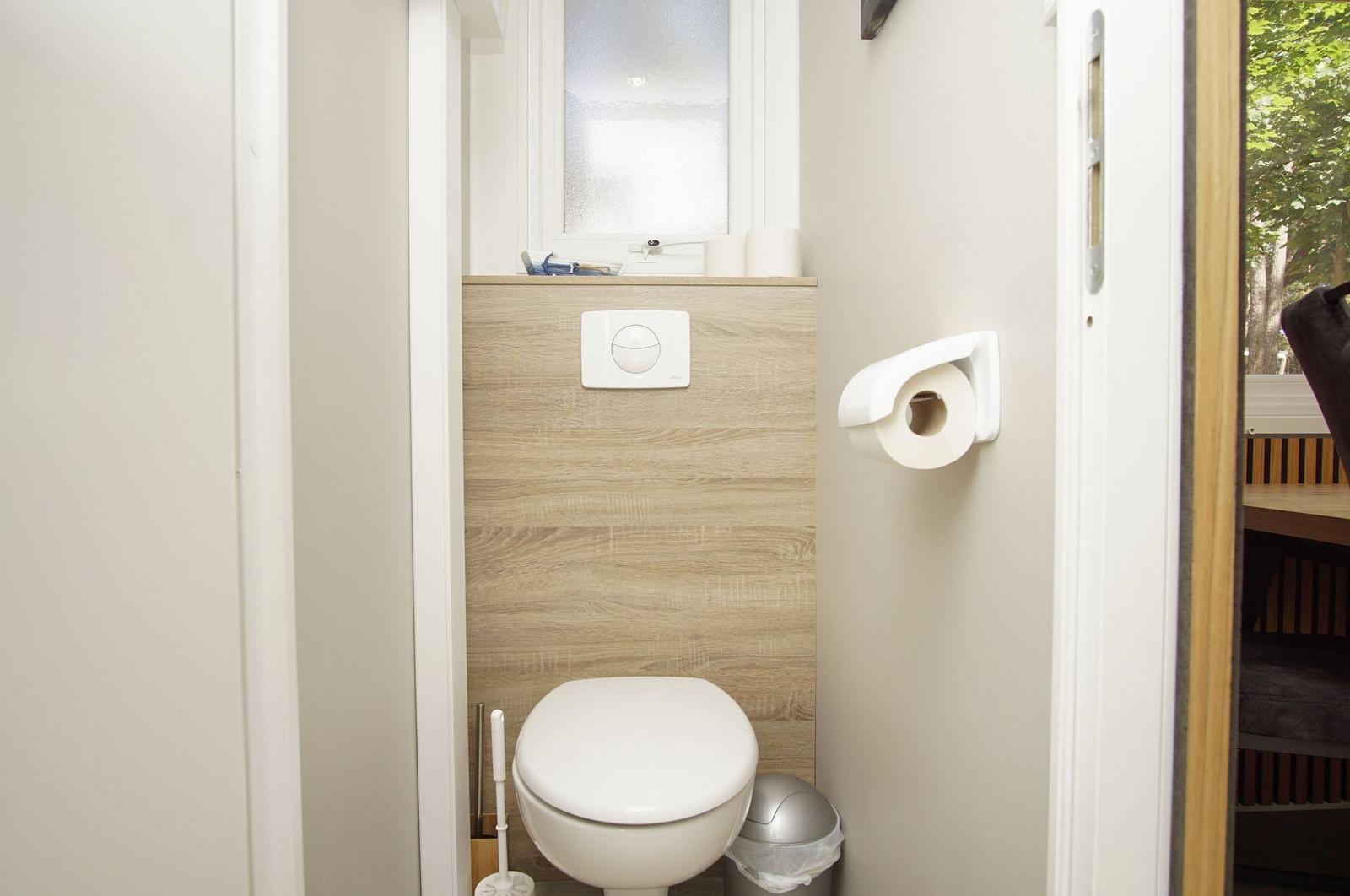 Toilette mit WC-Besteuerung, Toilettenpapierhalter und Fenster