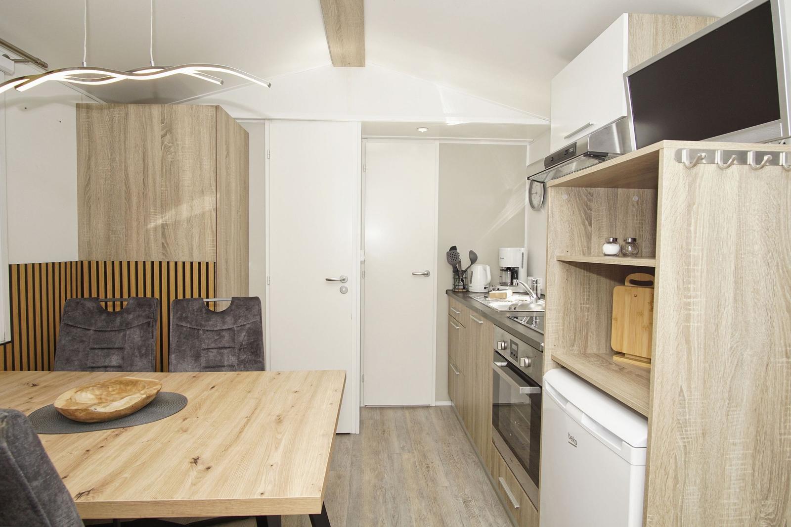 Küche mit Essbereich, Holztisch, Schränke und Kochgeräten.