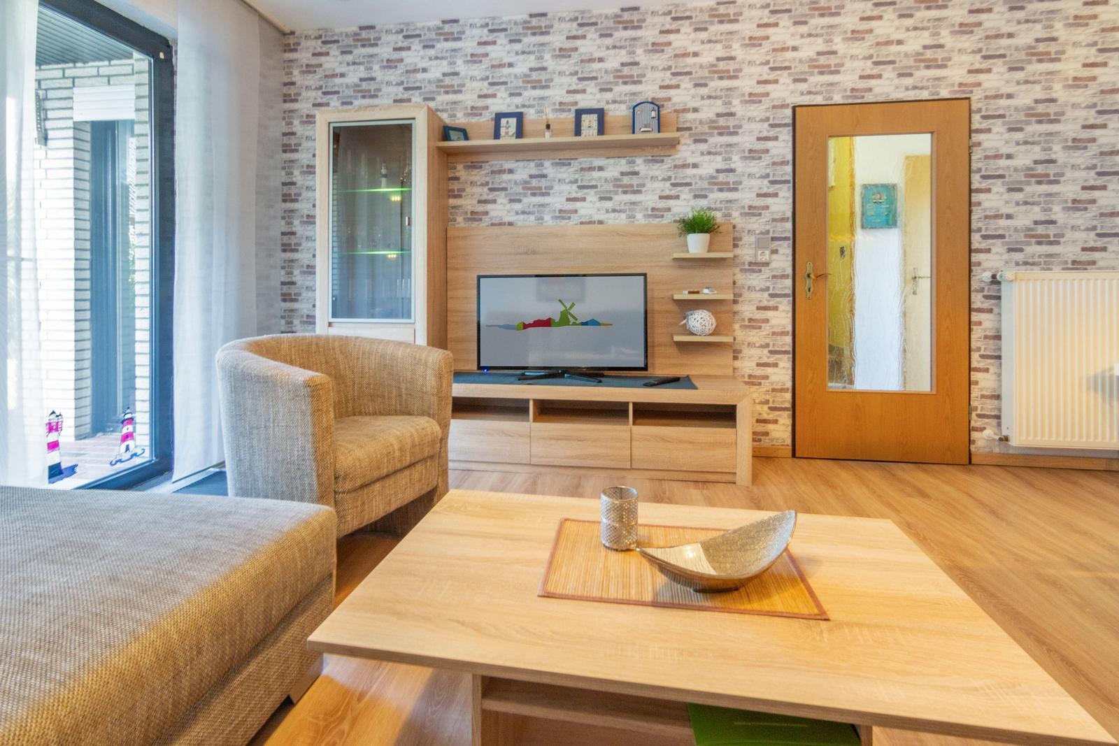 Wohnzimmer mit Holzmöbeln, Fernseher und Backsteinwand.