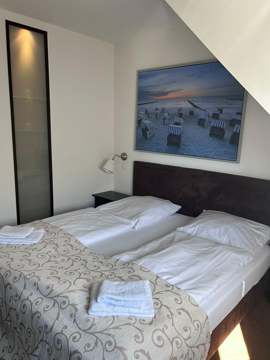 Schlafzimmer mit Doppelbett, Wandbild und Kleiderschrank.