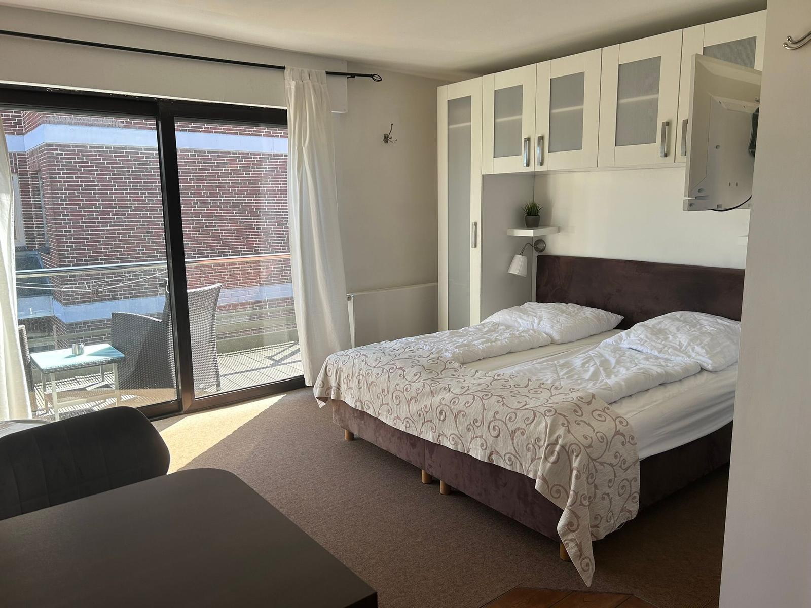 Schlafzimmer mit Doppelbett, Balkon und weißen Schränken.