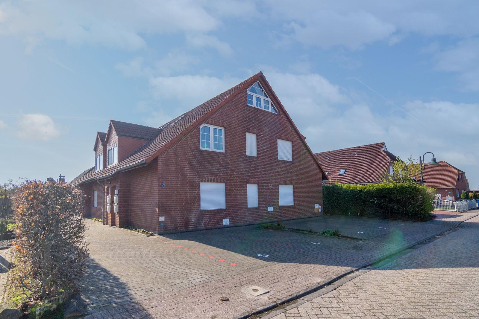 Rotes Backsteinhaus mit Dachgauben und Garage. Vorhof mit gepflastertem Platz.