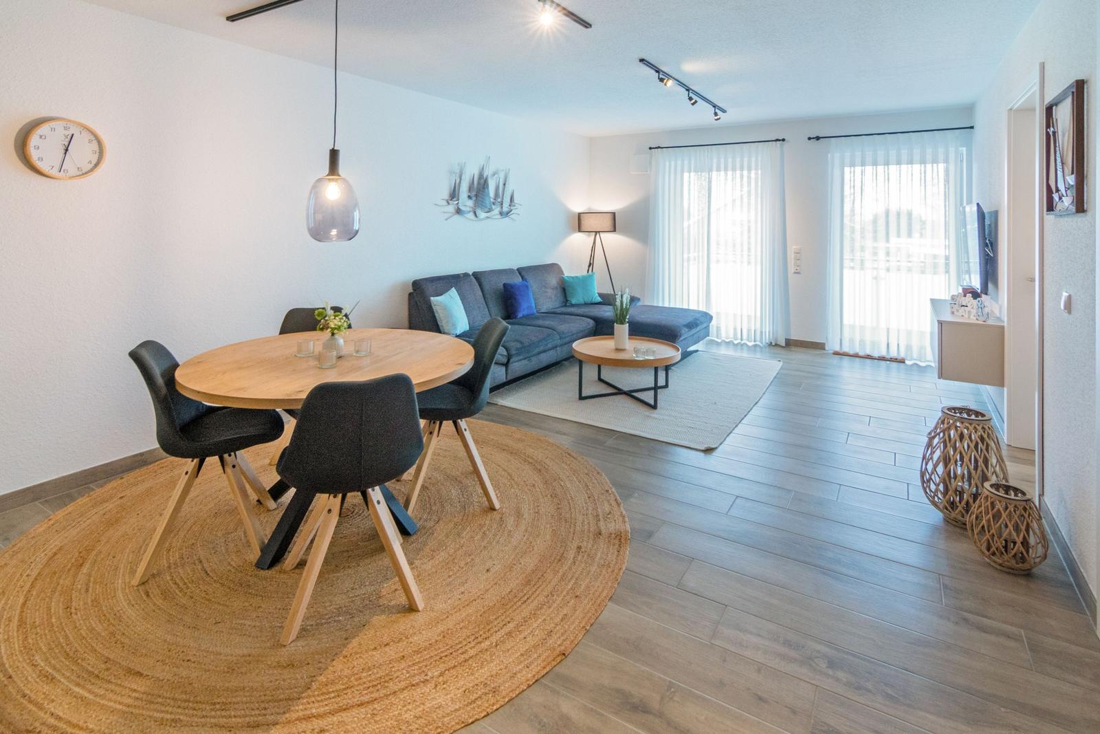 Wohn- und Essbereich mit Sofa, runden Tisch und Holzboden.