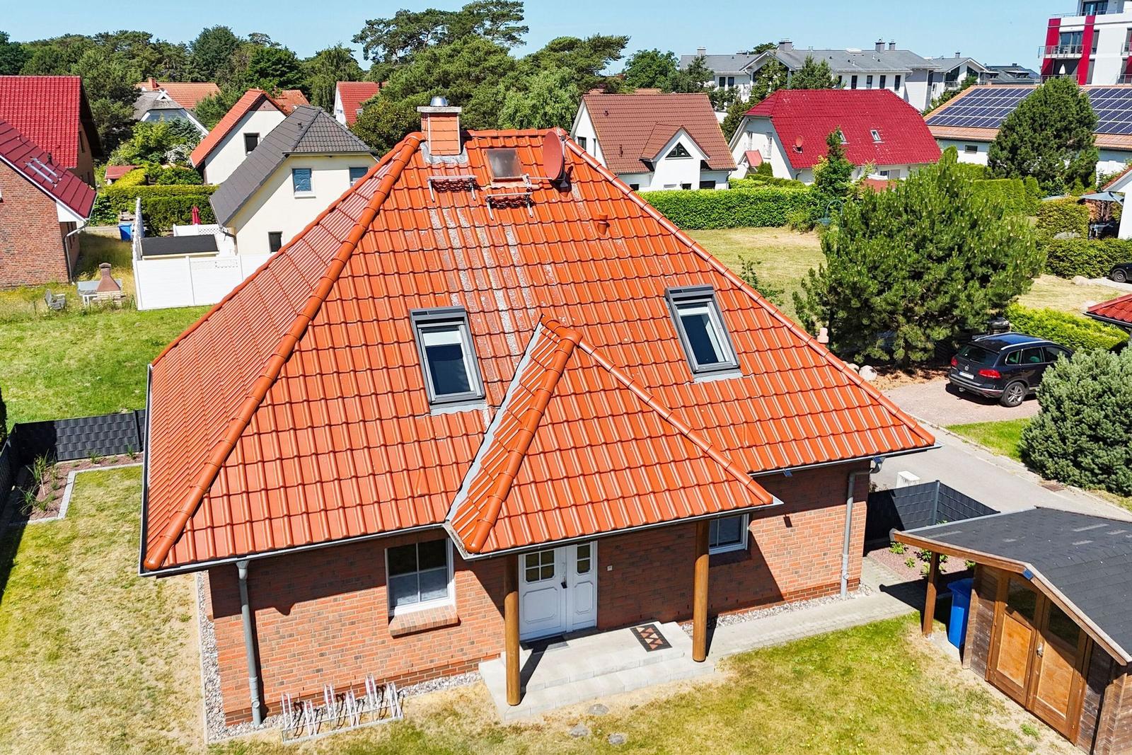 Ein Haus mit rotem Ziegeldach, weißer Tür und Garten.