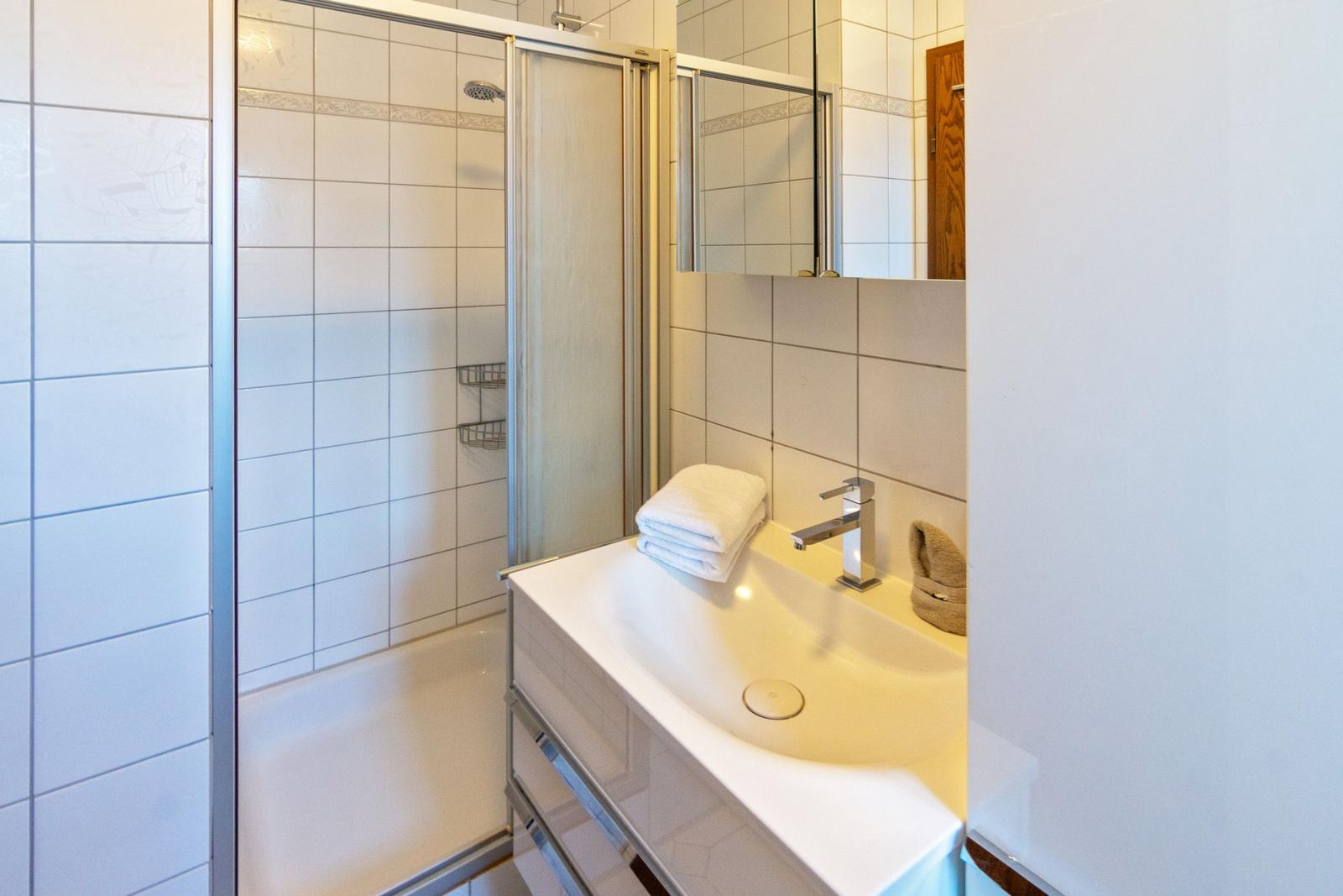 Badezimmer mit Dusche, Waschbecken und Spiegel