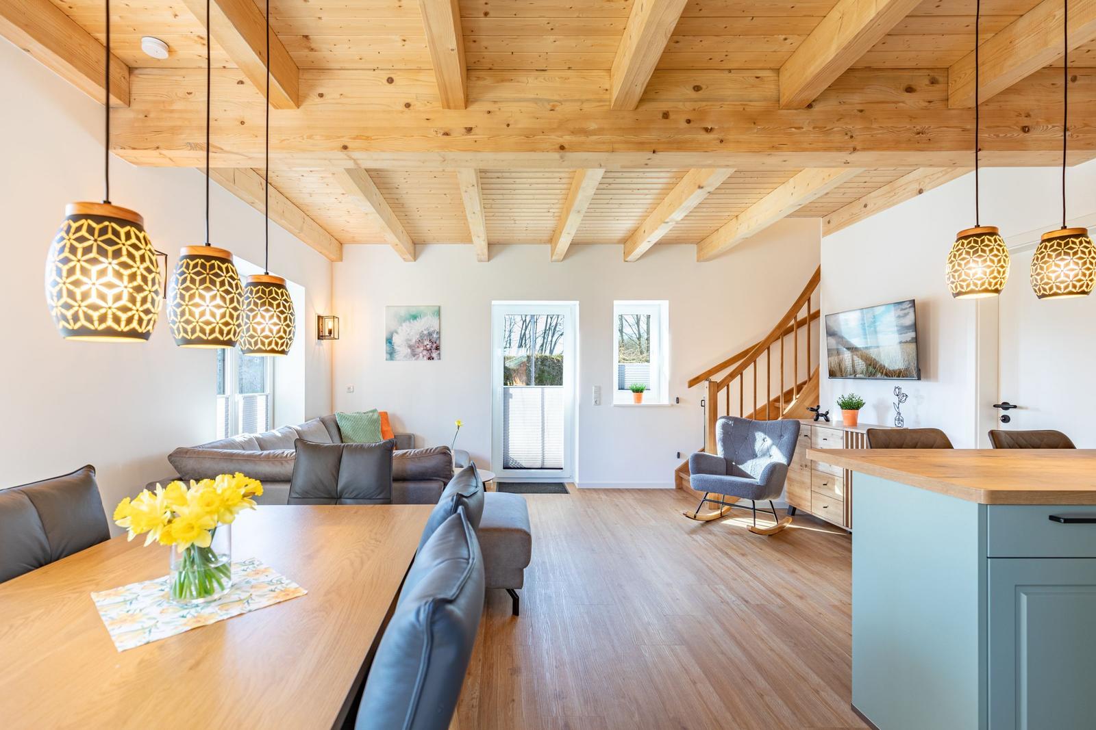 Wohn- und Essbereich mit Holzboden, Deckenbalken und Kücheninsel.
