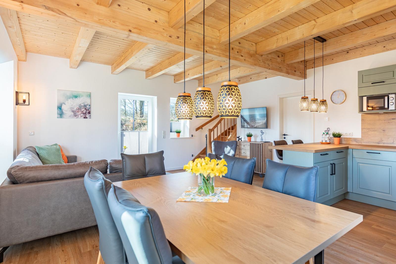 Essbereich mit Holztisch, blauen Stühlen und Küchenzeile mit hellblauen Schränken.
