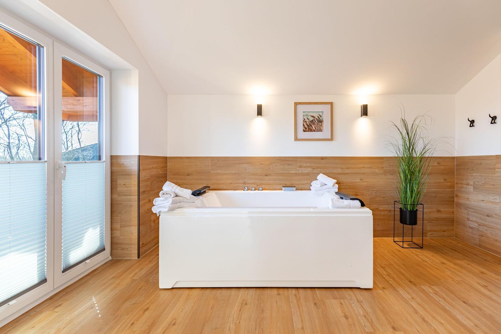 Bad mit Whirlpool, Holzwand und Fenster zur Aussicht.