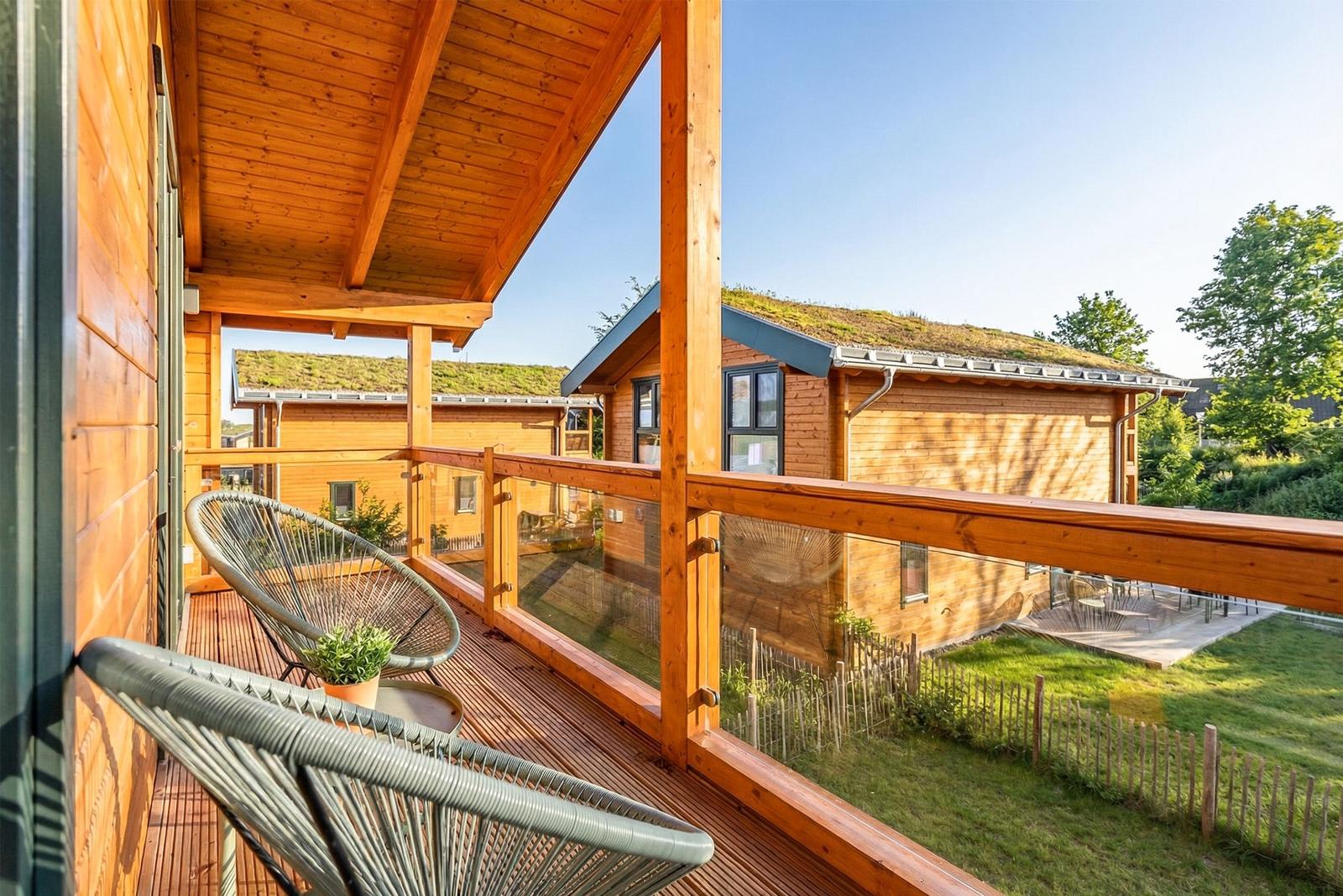 Holzterrasse mit Sitzgelegenheiten und Blick auf grüne Umgebung und Nachbarhäuser.