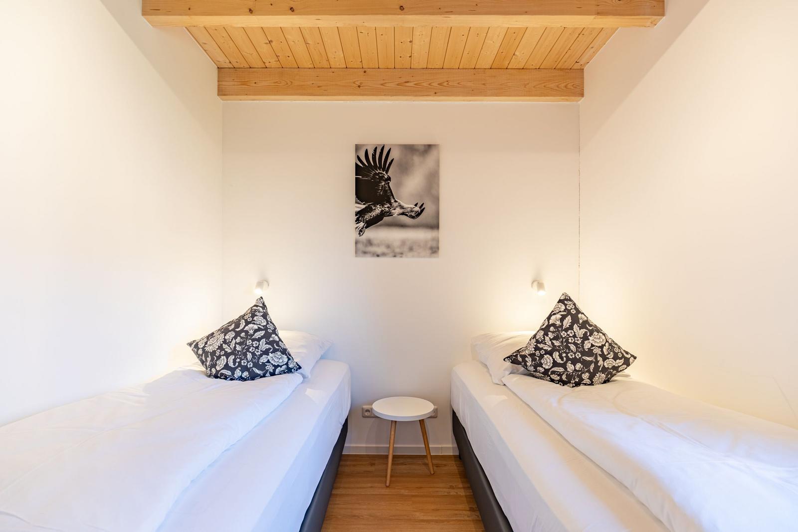 Zwei Einzelbetten mit Kissen, Wandbild und Holzdecke