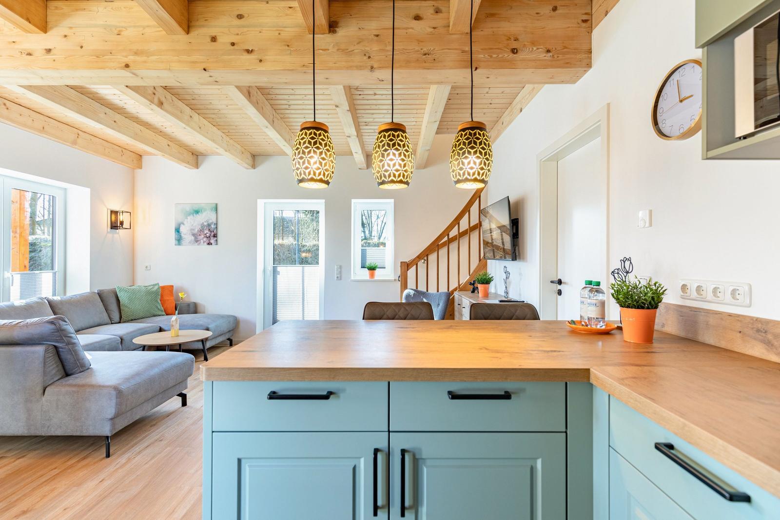 Küche mit Holzoberfläche und blauen Schränken. Wohnbereich mit Sofa und Holzdecke.
