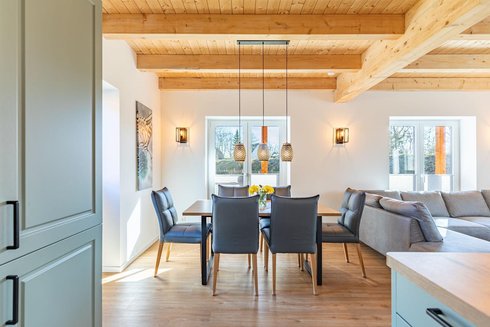 Essbereich mit Tisch, Stühlen und Sofa unter Holzbalkendecke