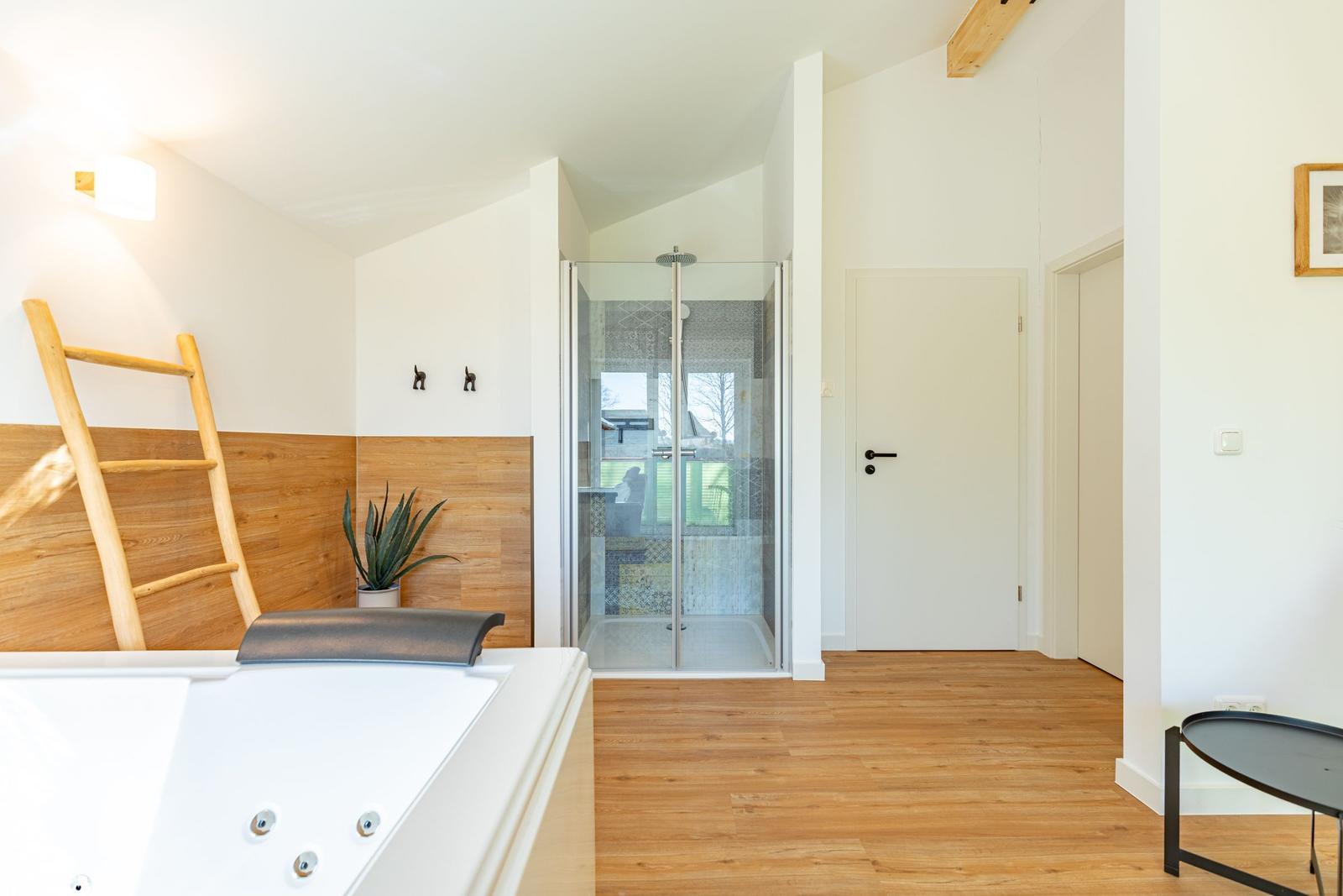 Dusche mit Glaswand, Whirlpool und Holzfußboden
