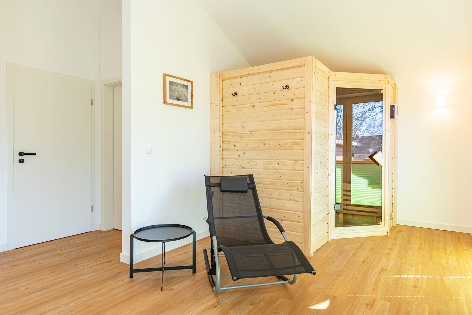 Sauna mit Holzwand und Sitzgelegenheit im Raum mit Holzboden.