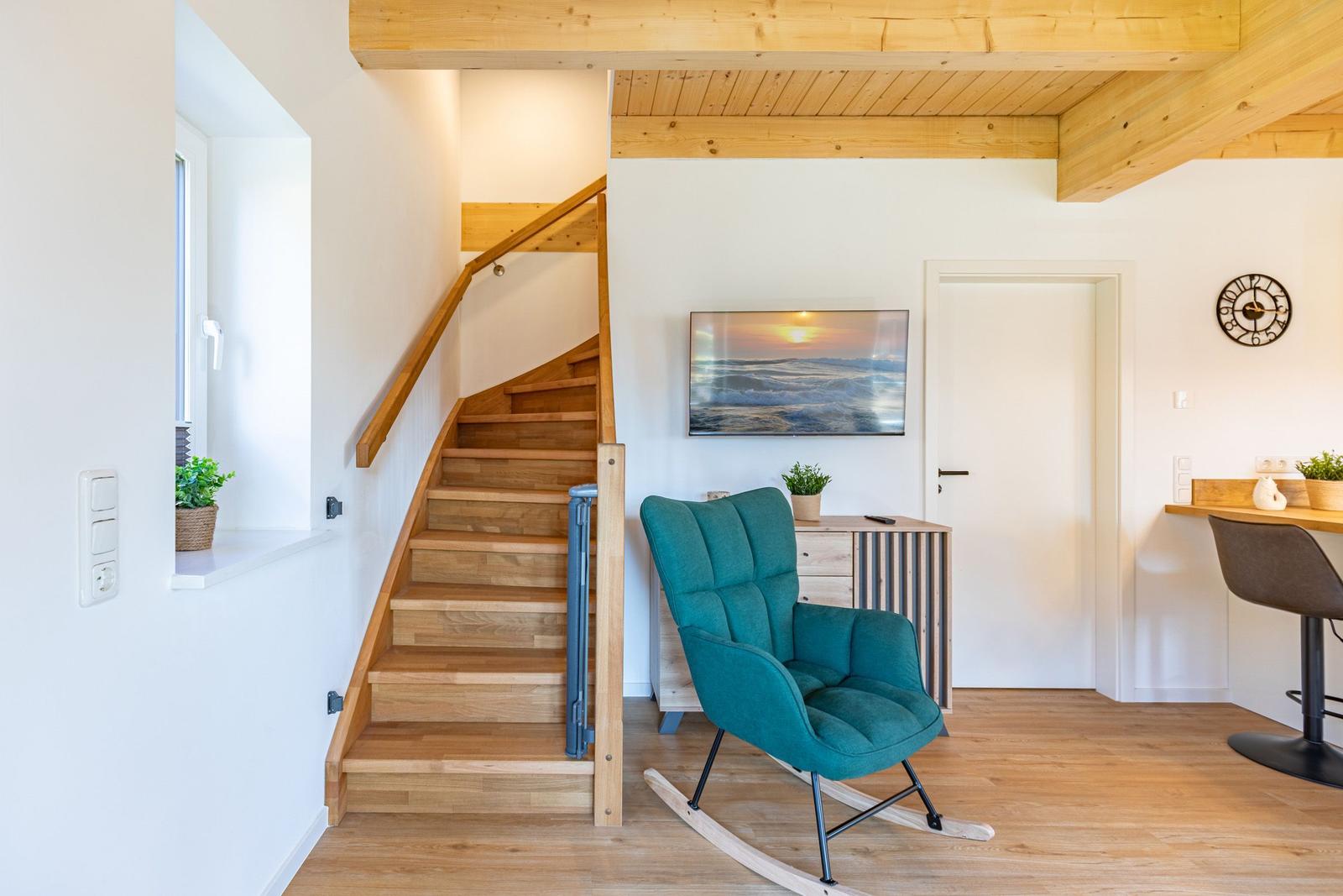 Holztreppe mit Sitzgelegenheit, Fernseher und Küchenbereich im Wohnraum.