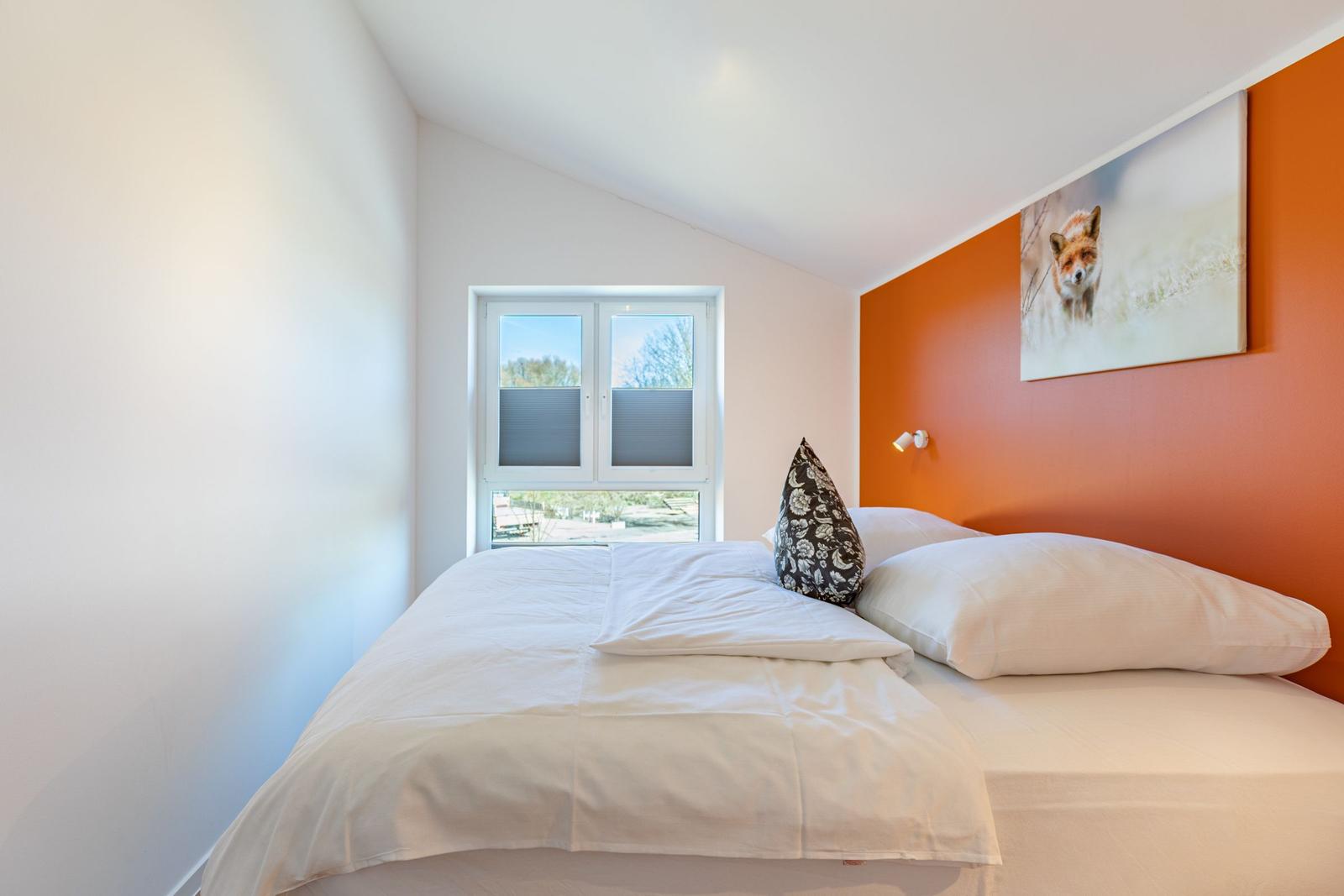 Schlafzimmer mit Bett, Fenster und Wandbild eines Fuchses.