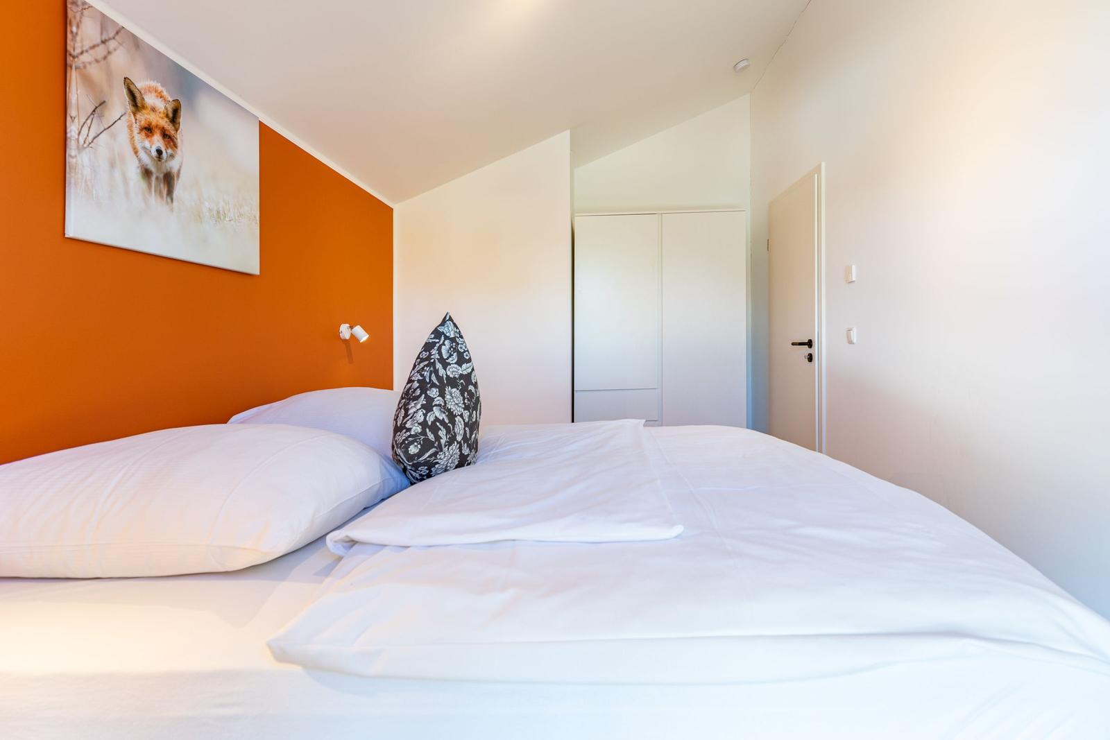 Schlafzimmer mit Bett, Wandbild eines Fuchses und Schrank.