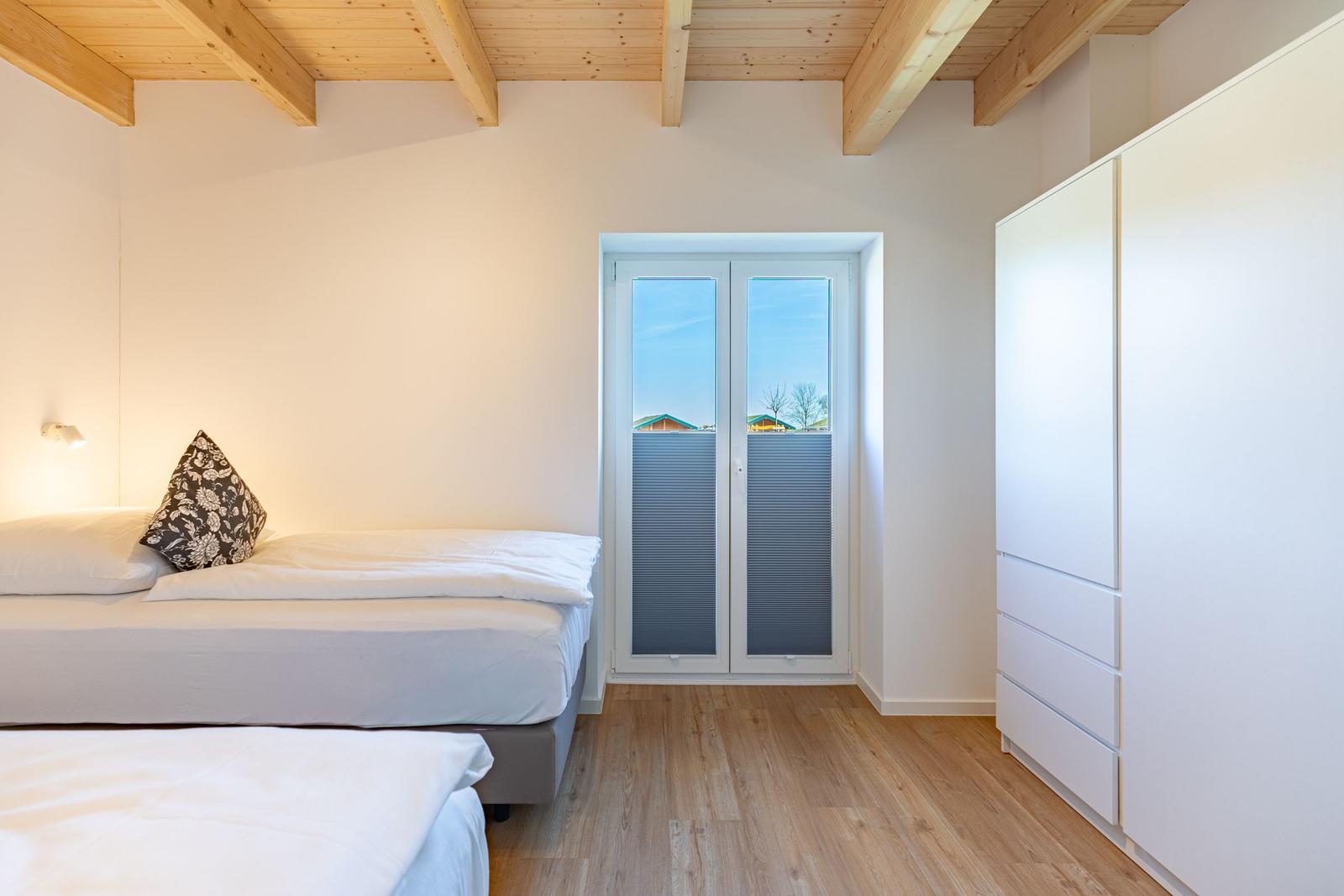 Schlafzimmer mit Doppelbett, Holzboden und Fenster zur Aussicht.