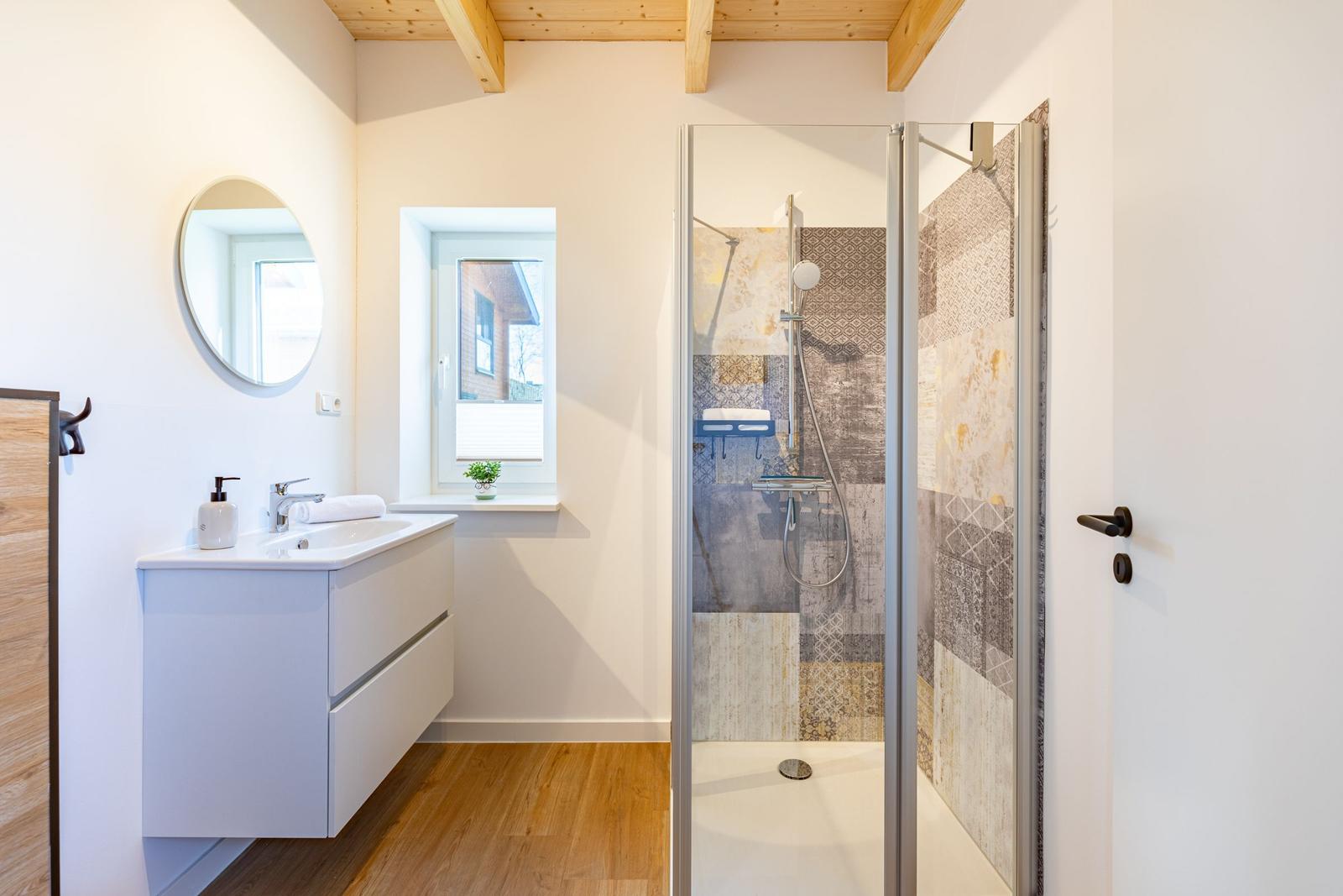 Badezimmer mit Dusche, Waschbecken und Fenster