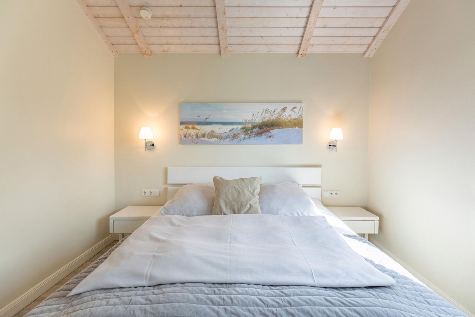 Schlafzimmer mit Bett, Nachttischen und Wandbild. Holzdecke und Beleuchtung.