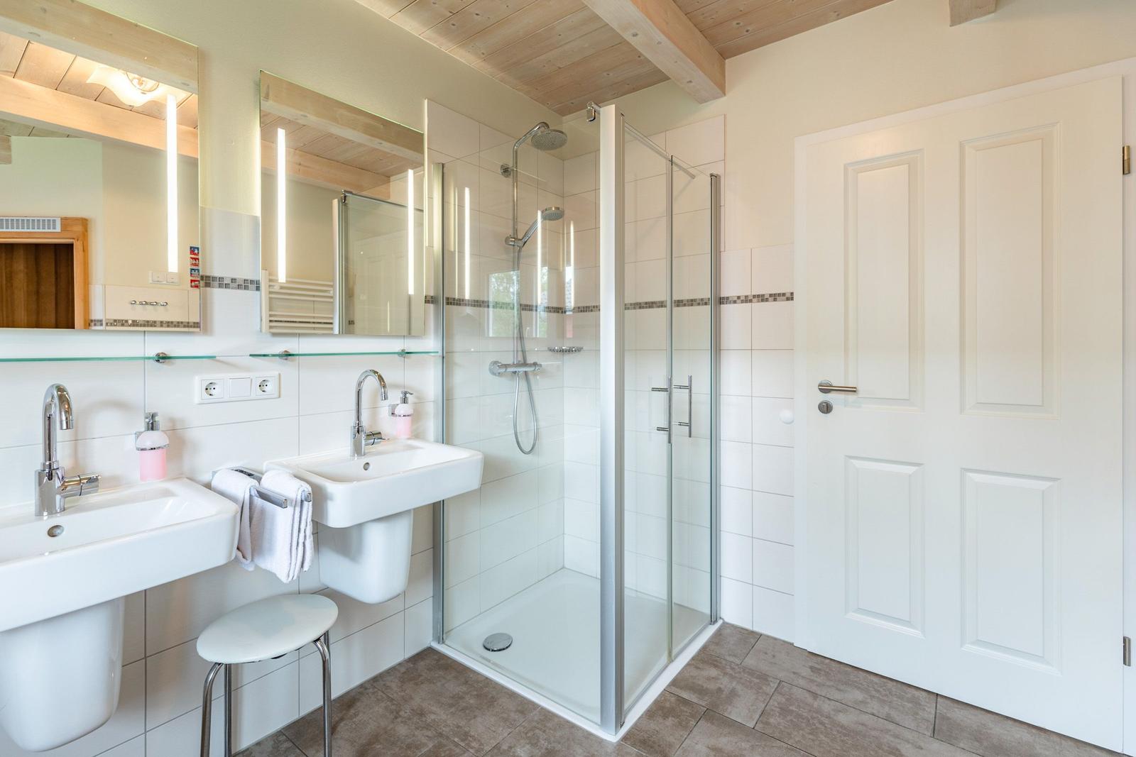 Badezimmer mit Dusche, zwei Waschbecken und Spiegeln