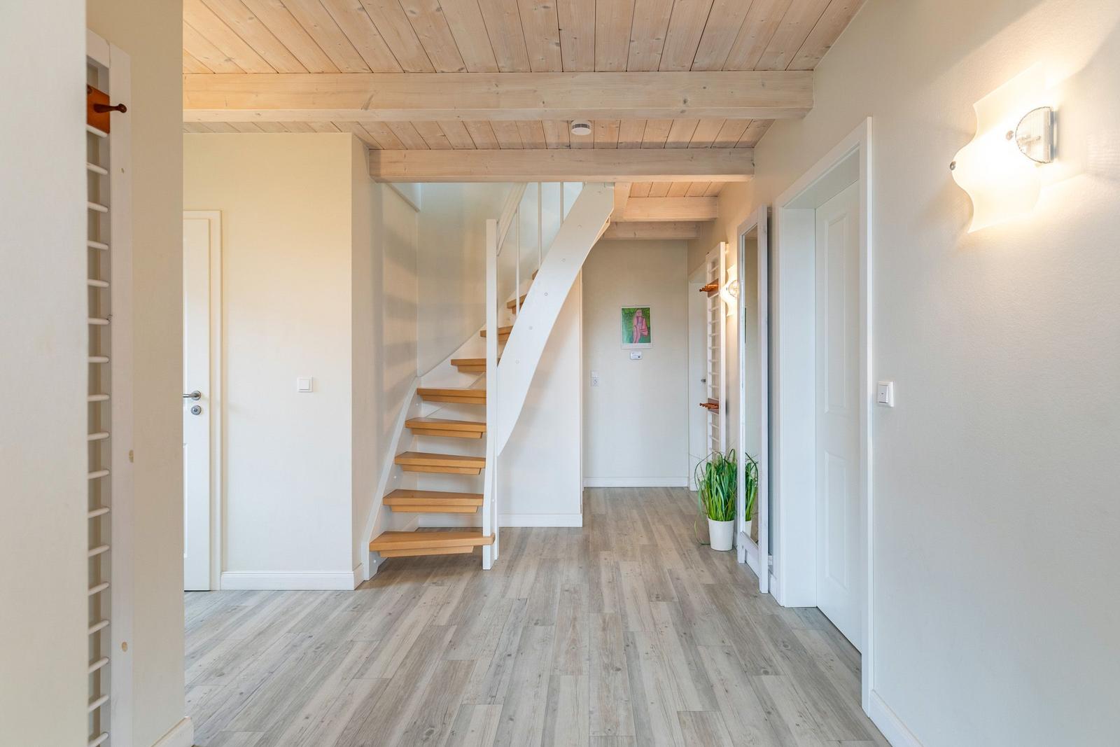 Hausgang mit Holztreppe und hellen Wänden. Holzdecke und Bodenbelag.