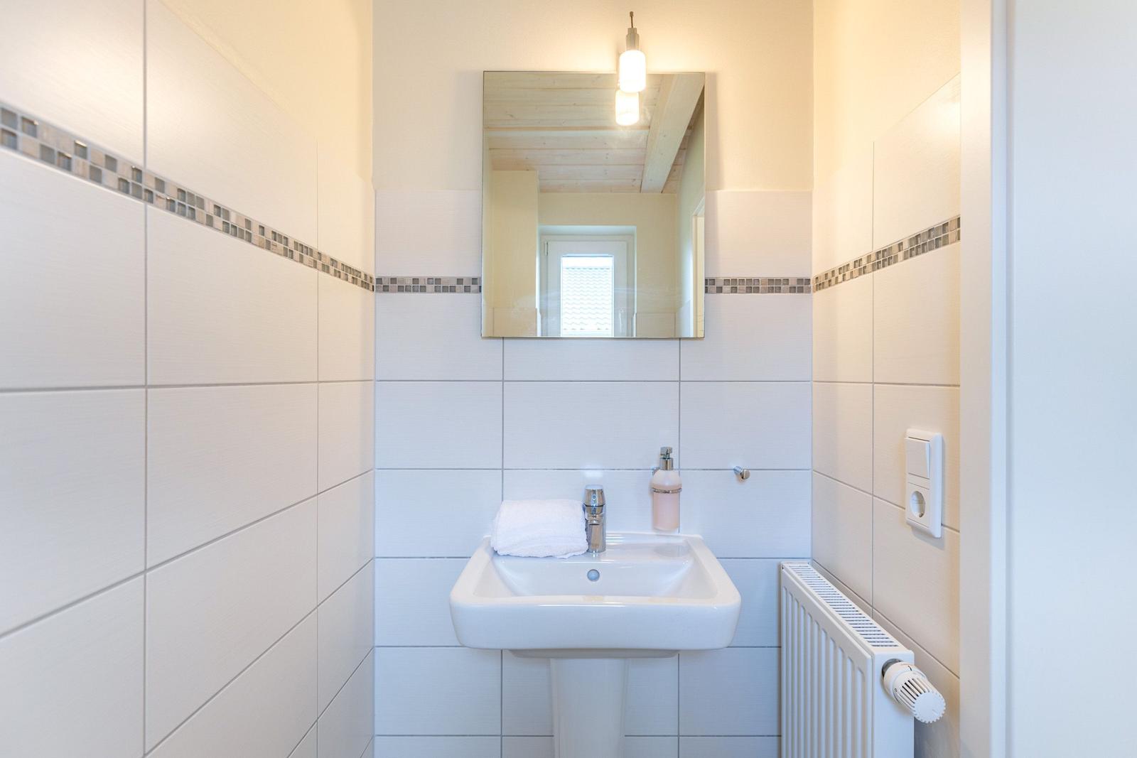 Badezimmer mit Waschbecken, Spiegel und Heizkörper an der Wand.