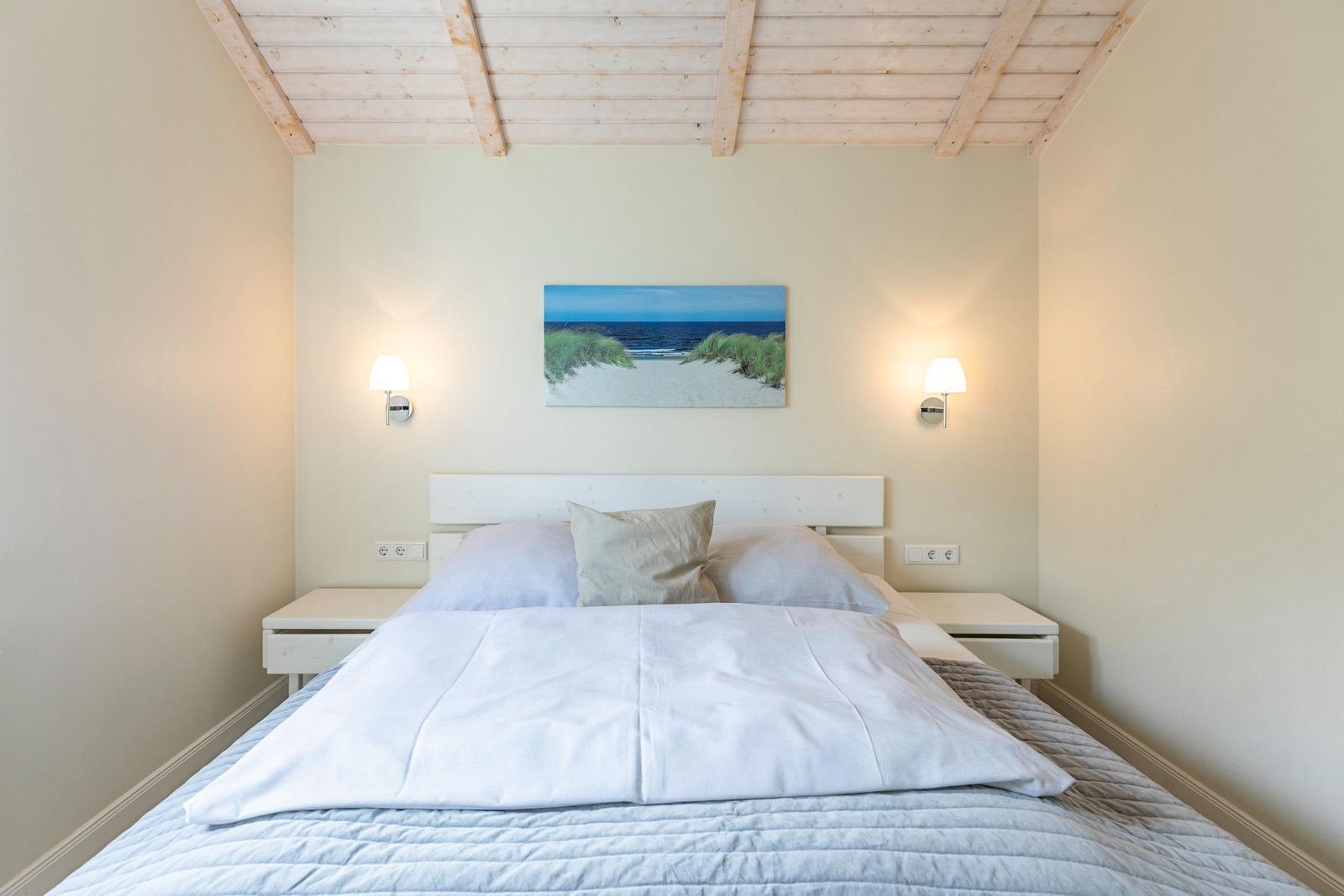 Schlafzimmer mit Bett, Nachttischen und Wandbild. Holzdecke und Stehlampen.