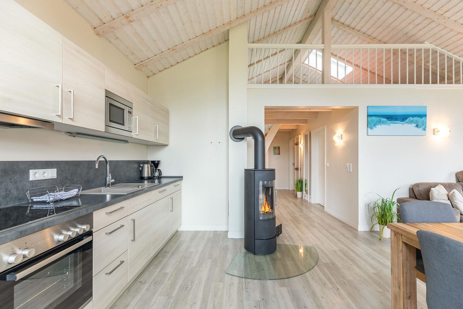 Küche mit Herd und Mikrowelle, Wohnbereich mit Kamin und Balkon.