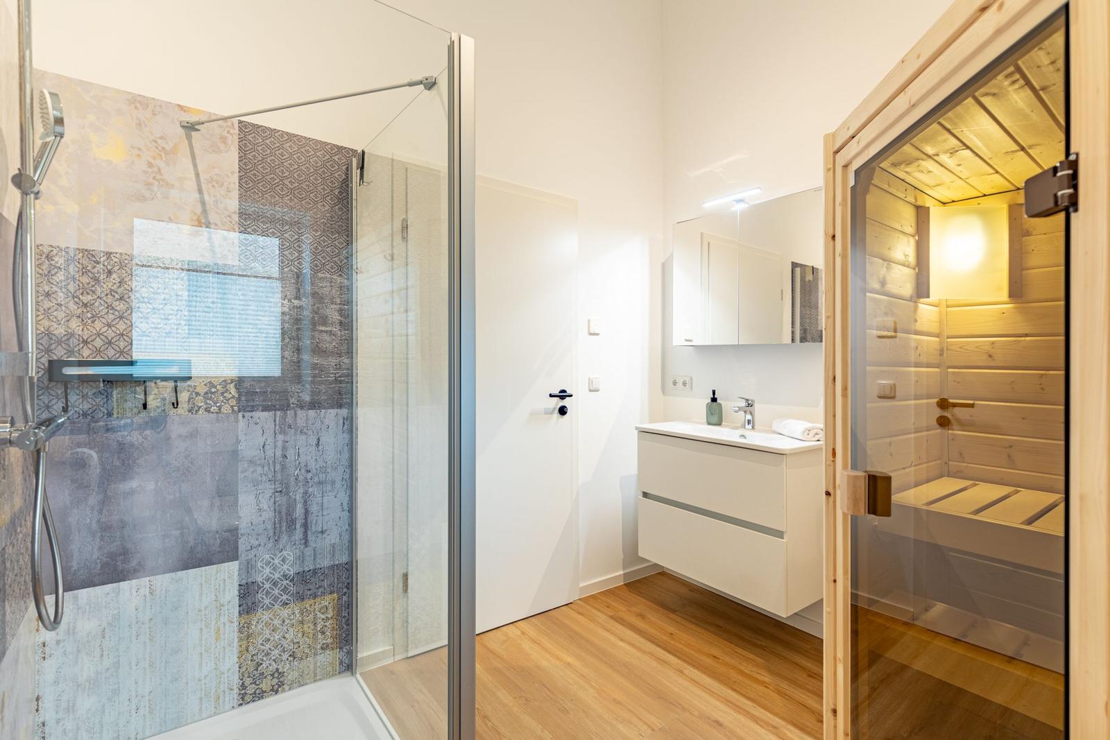 Badezimmer mit Dusche, Waschbecken und Sauna