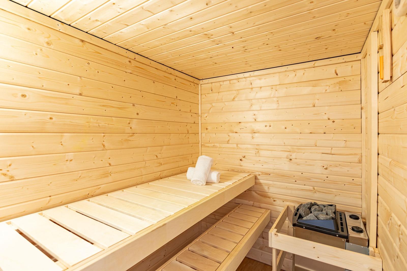 Sauna mit Holzwand, Bank und Heizung. Handtuch liegt auf der Bank.