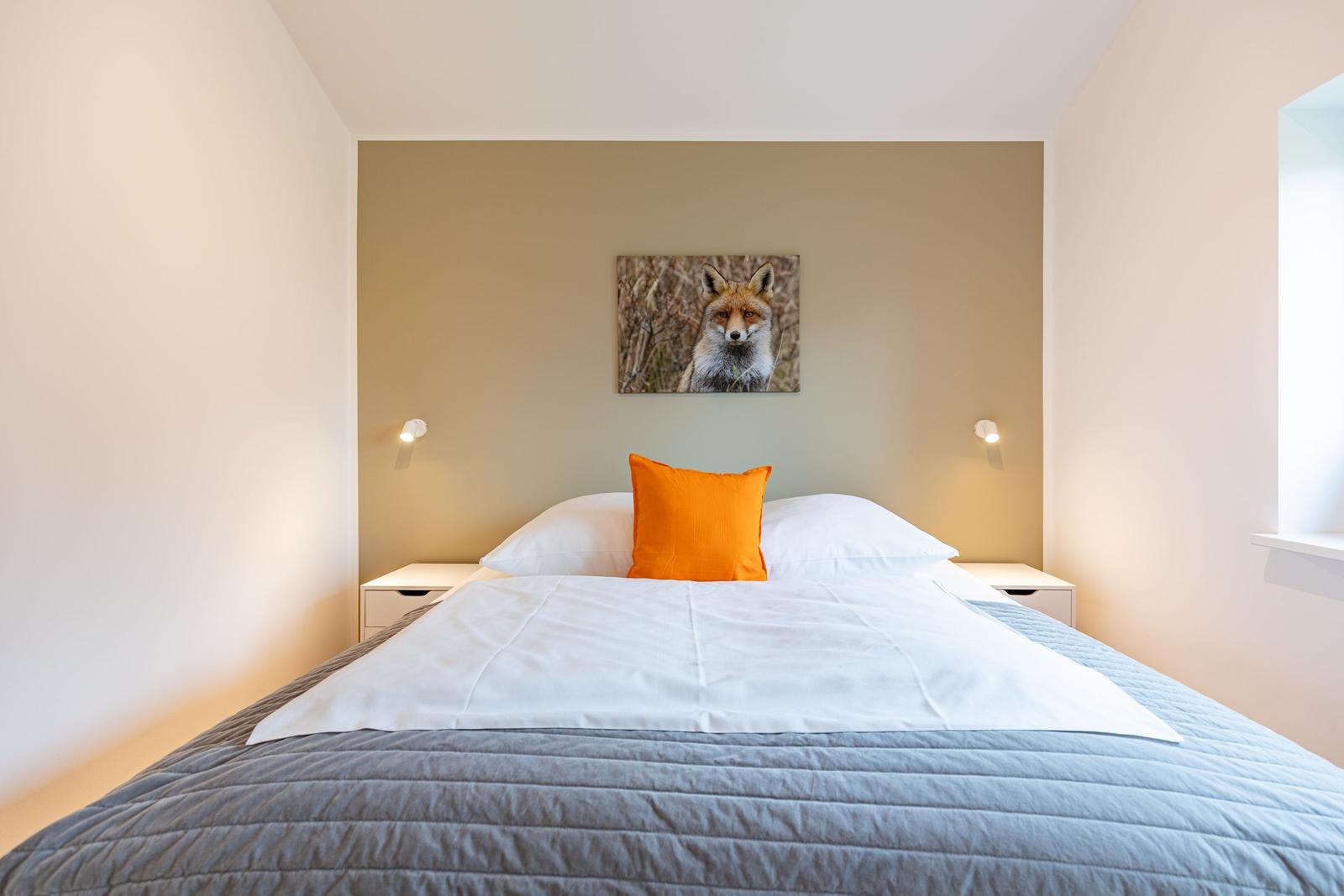 Schlafzimmer mit Bett, Kissen und Wandbild eines Fuchses.