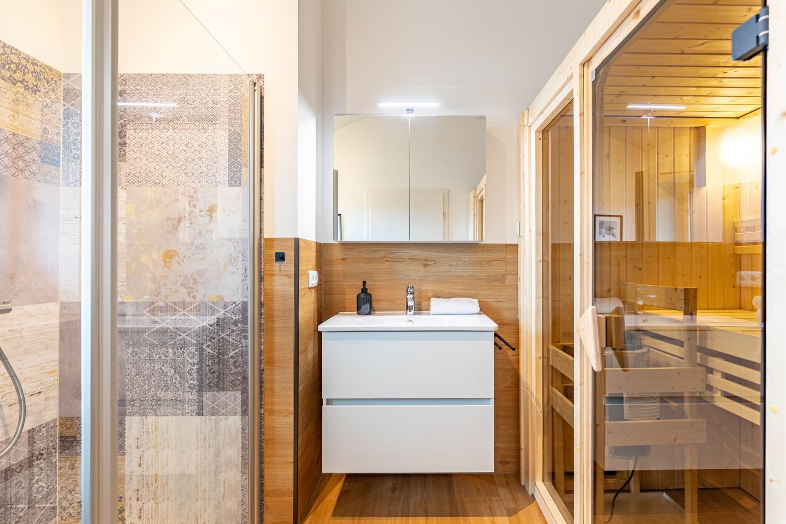 Badezimmer mit Dusche, Waschtisch und Sauna
