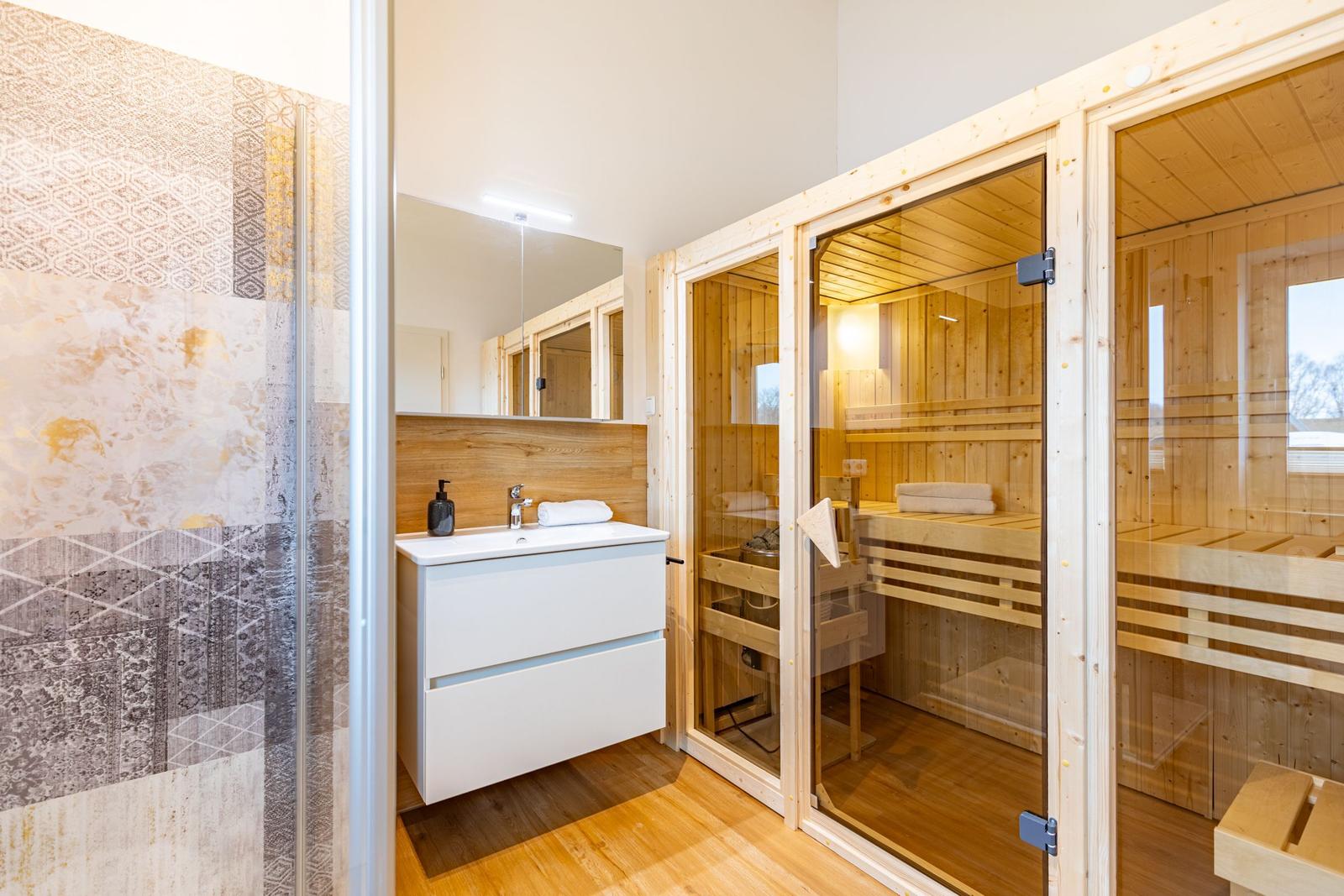 Bad mit Dusche, Waschbecken und Sauna im Holzdesign.