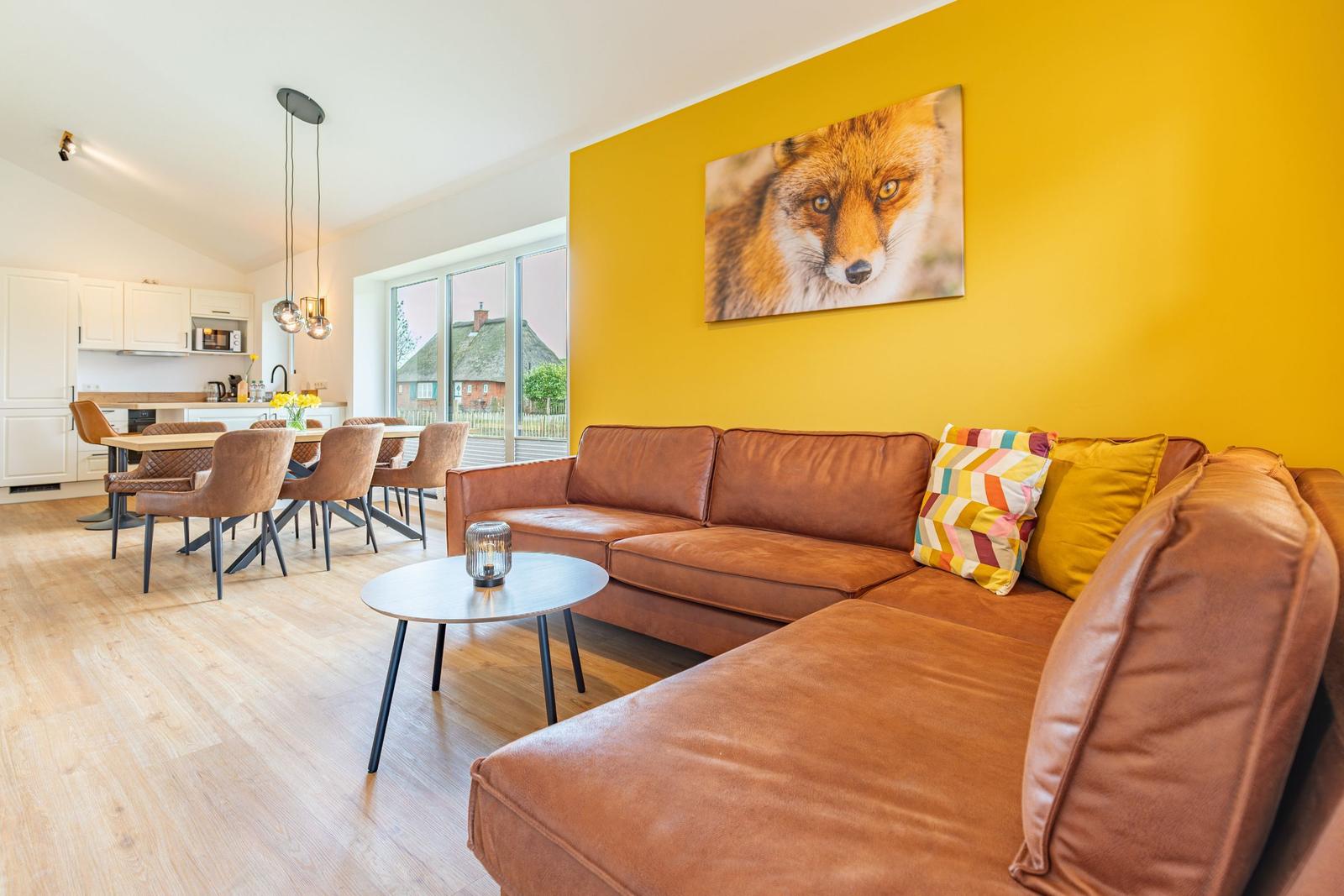 Ein Wohnzimmer mit braunem Sofa, gelber Wand und Wandbild eines Fuchses.