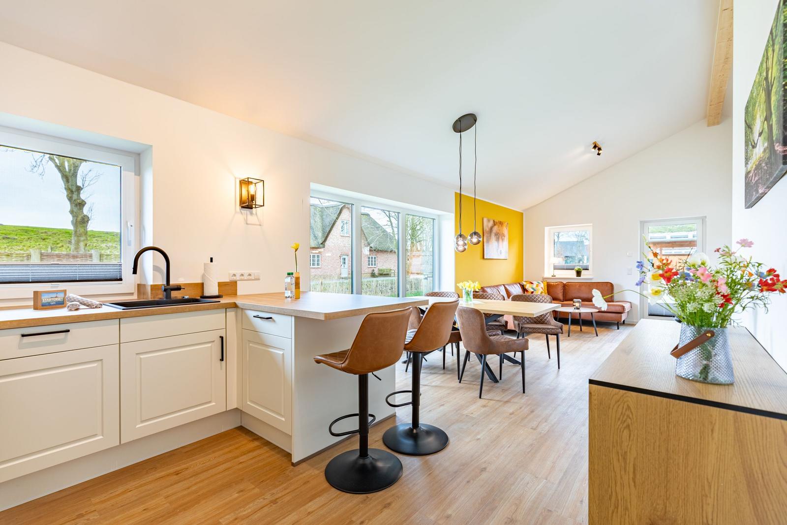 Küche mit Essbereich und Wohnzimmer mit braunen Sitzgelegenheiten und Holzboden.