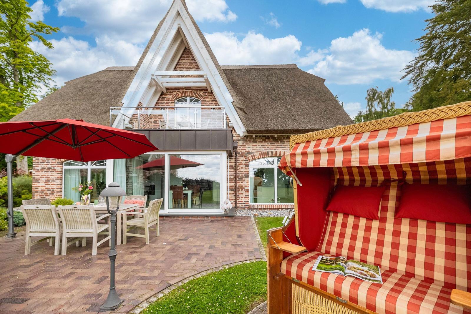 Haus mit Dachterrasse, Gartenbereich und Strandkorb mit rot-weißem Muster.