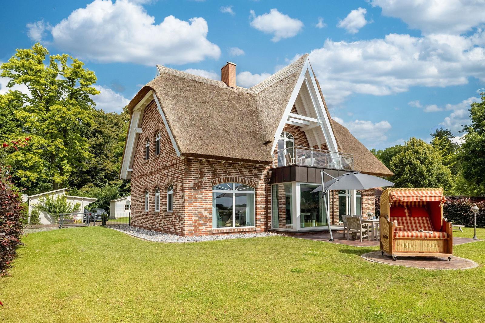 Haus mit Strohdach, Terrasse und Strandkorb im Garten